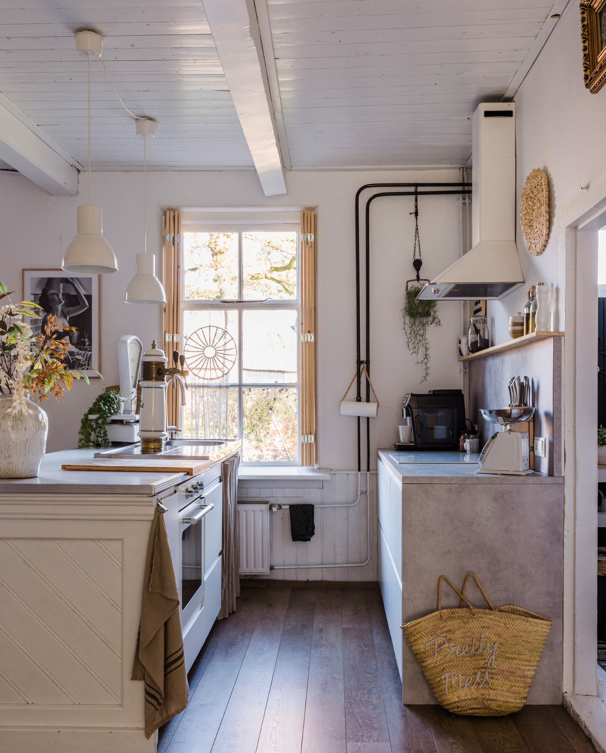 Macramé hanger, luiken, gordijn onder spoelbak en keukenrolhouder zelfgemaakt. Keukenkasten, betonlook werkblad, apparatuur, barkrukken, lampen, messenblok, glazen flessen, pepermolen en snijplank Ikea. Bar en antieke Grolschtap stonden al in het huis, geschilderd in Ral 9016. Koffiemachine Philips. Theedoek Loods 5, tas Noa May, Berkel-weegschaal Marktplaats, zwart-wit poster Poster Store. Vaas en zijden bloemen MK Objecten. Kommen HKliving, koffiekoppen Douwe Egberts, zwarte handdoek Hema, vloer Quick-Step. Verf muren en lambrisering Ral 9016. vtwonen 12-2023 | styling Anouschka Witteveen | fotografie Corine Hoge Bavel