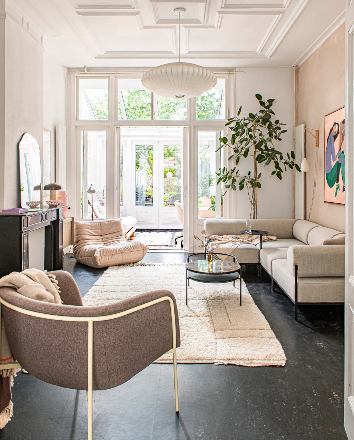 Lamp Saucer Bubble van George Nelson, schilderij van Anne Mei Poppe, bank Noah Living, koffietafel Woud, fauteuil Togo van Ligne Roset, roze vaas Malwina Konopacka, vloerlamp Arne Jacobsen voor Louis Poulsen, alle muurverf Kalkliter. Lamp, schaal en spiegel op schoorsteen vintage. Spiegel en vloerkleed HKliving. Stoel voorgrond Hübsch. Overig onbekend. vtwonen 12-2023 | productie De Binnenkijkers | styling  Jeske Weel | fotografie Caroline Coehorst