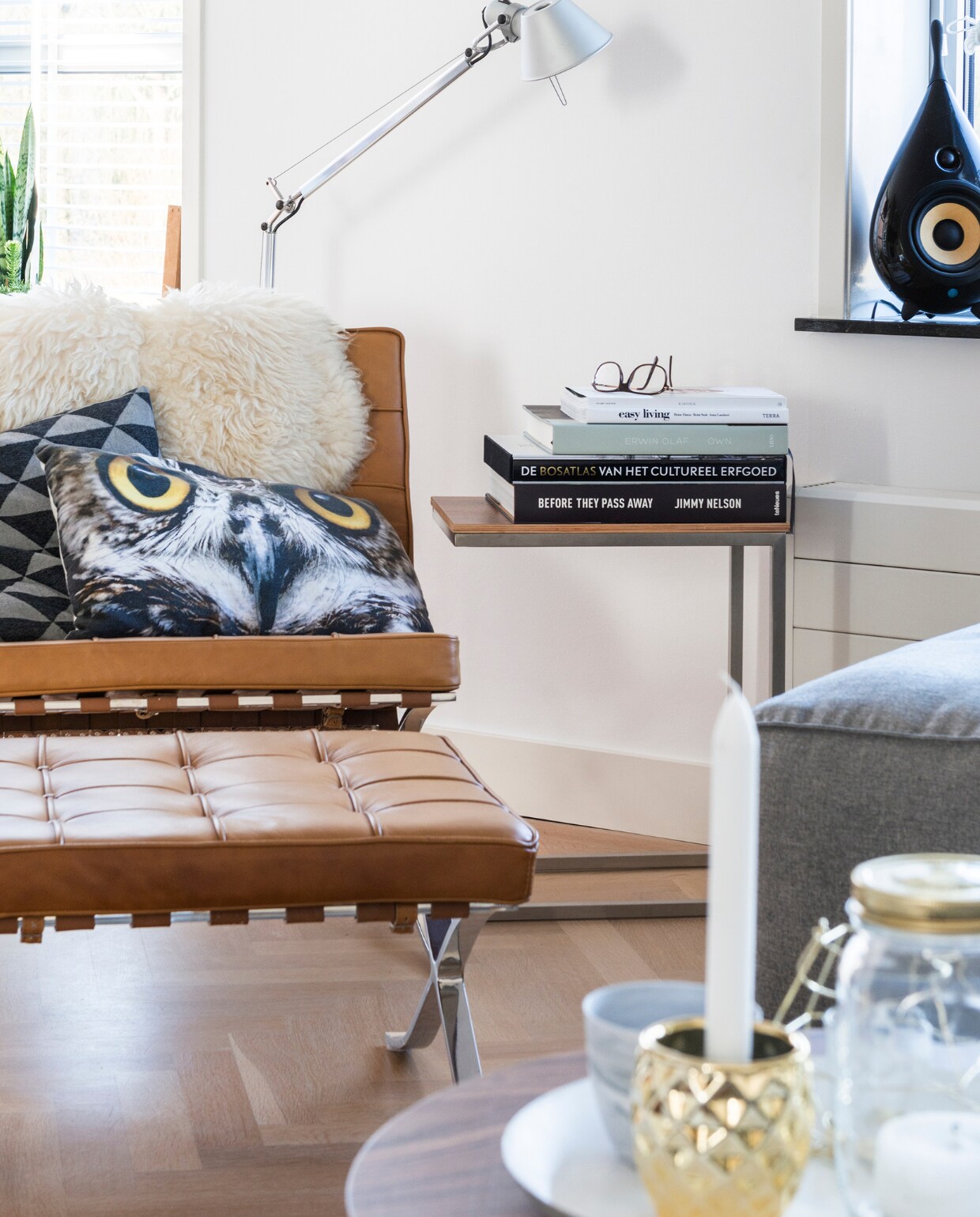 Glazen pot van Dille en Kamille, dienblad van Hema, driepoot bijzettafel van Loods 5, kopje van House Doctor.De druppelvormige speaker is van Scandyna. Barcelona Chair en kussen met uil van Loods 5. De schapenvacht is van Ikea, het kussen met driehoekjes kochten ze bij Hema. Q4 side table met erop een stapeltje kunstboeken. De Tolomeo lamp met staande poot is van Artemide. Achter de fauteuil een zelfgemaakt tafeltje vol planten. Overig onbekend. vtwonen 12-2015 | fotografie Stan Koolen