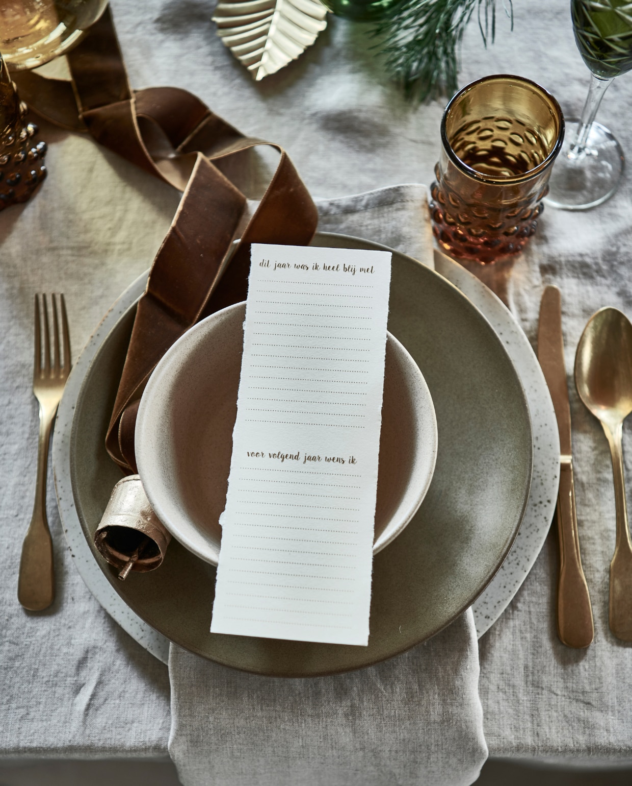Groen champagneglas, set van 6 (polspotten.nl). Beige gespikkeld bord (nordal.eu). Groen bord, beige kom, allebei van Studio Ro Smit (factor-ij.amsterdam). Stonewashed gouden bestek, okergele glazen XL kerstbal (paviljoennoord.com). Gouden kandelaar in vorm van ster (weldaad.com). Gouden blaadjes, set van 3 (bungalow.dk). Gouden mini-kandelaar, kaars van bijenwas, set van 4, gouden kaarssteker in vorm van aureool (letoile.store). Smalle hoge groene blokkaars (allestedlund.com).2 Papieren ster, papieren doos, set van 2 (bungalow.dk). Okergele poef (vantil.nl).3 Linnen tafelkleed, servet, set van 2 (hm.com). Groen bord, beige kom, allebei aardewerk van Studio Ro Smit (factor-ij.amsterdam). Okergeel waterglas, stonewashed gouden bestek, (paviljoennoord.com). Beige gespikkeld bord (nordal.eu). Groen champagneglas, set van 6 (polspotten.nl). Gouden kerstbal in vorm van bel set van 2, gouden blad, set van 3 (bungalow.dk). vtwonen 12-2021 | styling Danielle Verheul | fotografie Sjoerd Eickmans