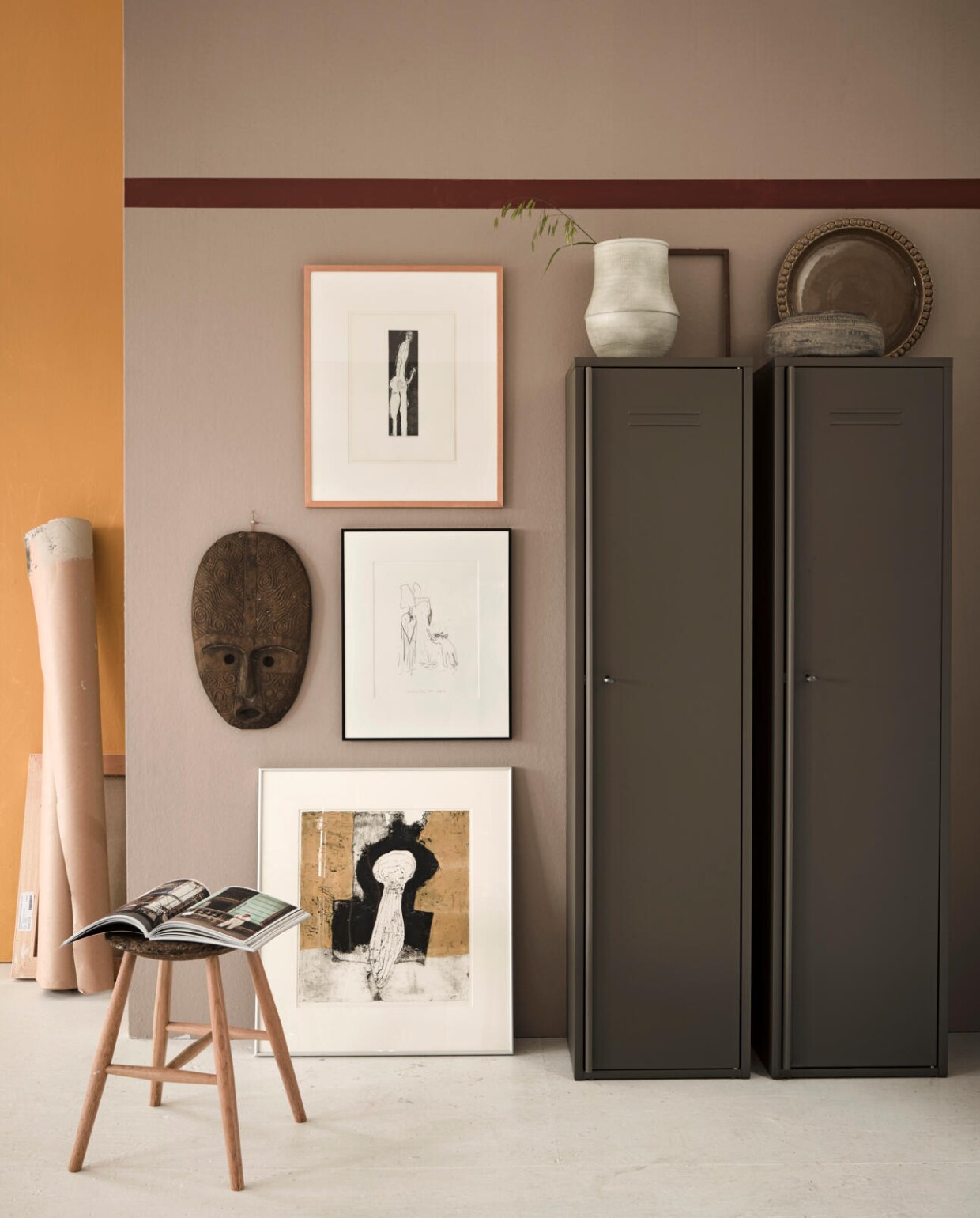 Op de wand vooraan Somerset Mauve, wand achteraan Golden Majesty, streep van Cardinal Red, matte krijtverf (Pure &amp; Original). Stalen kast Ivar, 160x40x30 cm (hxbxd) (Ikea). Betonnen pot Ø 27 cm (Kwantum). Vaas Roel (Trendhopper). Schaal, houten masker (Loods 5). Houten lijstje (kringloopwinkel). Kruk privébezit. Kunst van SBK Kunstuitleen Amsterdam. vtwonen 05-2018 | styling Fietje Bruijn | fotografie Alexander van Berge