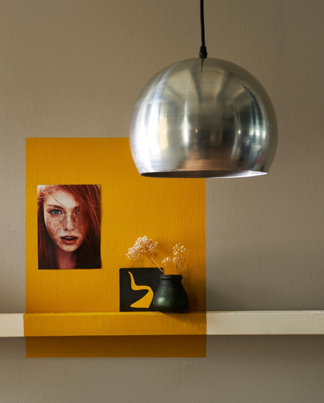 vtwonen collectie (muur in warm grey en een plank gelakt in linen, overschreven met een vlak in ochre). Het Kabinet (hanglamp), Casa Vivante (vaasje). Overig privébezit. vtwonen 06-2016 | styling Fietje Bruijn | fotografie Dennis Brandsma