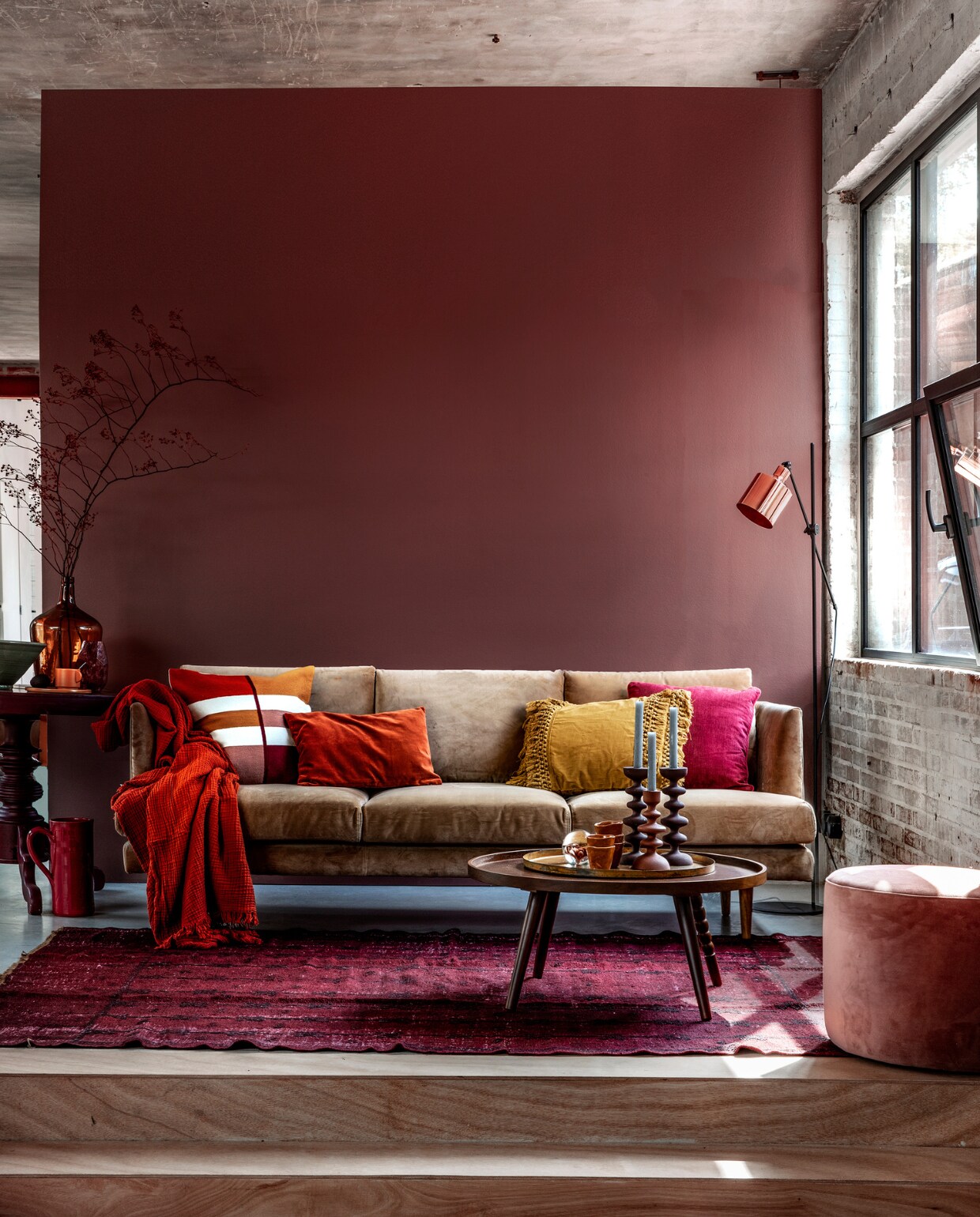 Muurverf Pure zijdemat Full Plum (Flexa). Beige velours 3-zitsbank Floyd, 214x88x81 cm (bxdxh), velours vintage Rosa poef (Sofacompany). Roestbruine crinkle plaid van Hay, vloerlamp Masterlight Industria 1020, hoogte 161 cm, okergeel kussen met franjes van Madam Stoltz (vtwonen.be). Kussen met gekleurde vlakken, roestbruin velours kussen, okergeel kopje, okergeel bord (H&amp;M Home). Donkerfuchsia kussen Milazzo Peony van Designers Guild (Wilhelmine van Aerssen). Wijnrode bijzettafel (Combitex). Donkergele flesvaas (Van Dijk &amp; Ko). Olijfgroene schaal, donkerrode kan (In-Petto). Vloerkleed (Ochre and Red). Salontafel Arabica van Dutchbone, kandelaars, presse-papier met bloem (Woondock). Roestbruine kopjes (Intratuin). vtwonen 11-2018 | Styling Moniek Visser | Fotografie Peggy Janssen