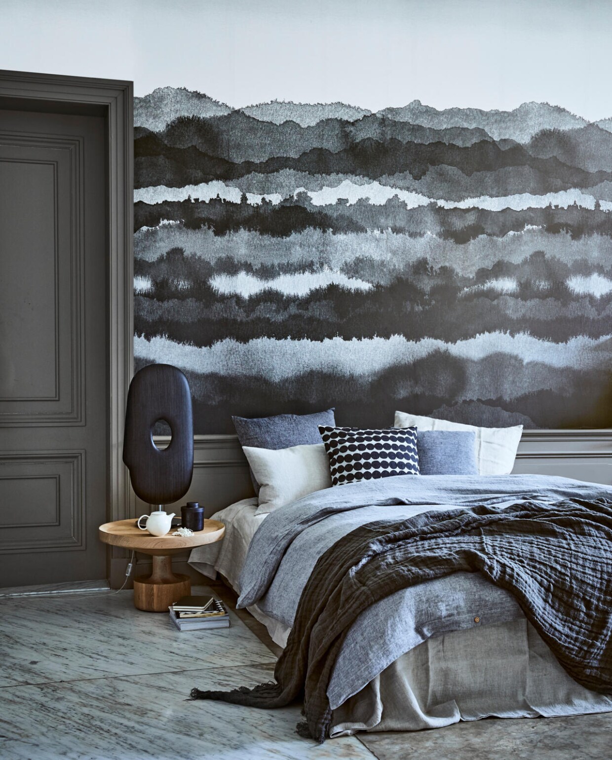 Behang Midnatt darkgrey van Sandberg, 180x270 cm (bxh) (De Ru). Eikenhouten bijzettafel Kigi (Linteloo). Lamp Mask van Moooi (Homestede). Theepotje Pebble, potje met deksel (Six and Sons). Laken Flax linnen 160x260 cm, dekbedovertrek Pebble linnen 200x200 cm, kussen Charcoal 60x60 cm, kussen Charcoal 50x50 cm, kussen Flax 40x60 cm, kussensloop Seashell linnen vanaf 60x70 cm (By Mölle). Kussen met stipdessin van Marimekko (&amp;Klevering). Ketting (Pols Potten). Plaid van grijs linnen, 130x170 cm (Hoffz). Boek en tijdschriften privébezit. vtwonen 02-2018 | styling Cleo Scheulderman | fotografie Jeroen van der Spek