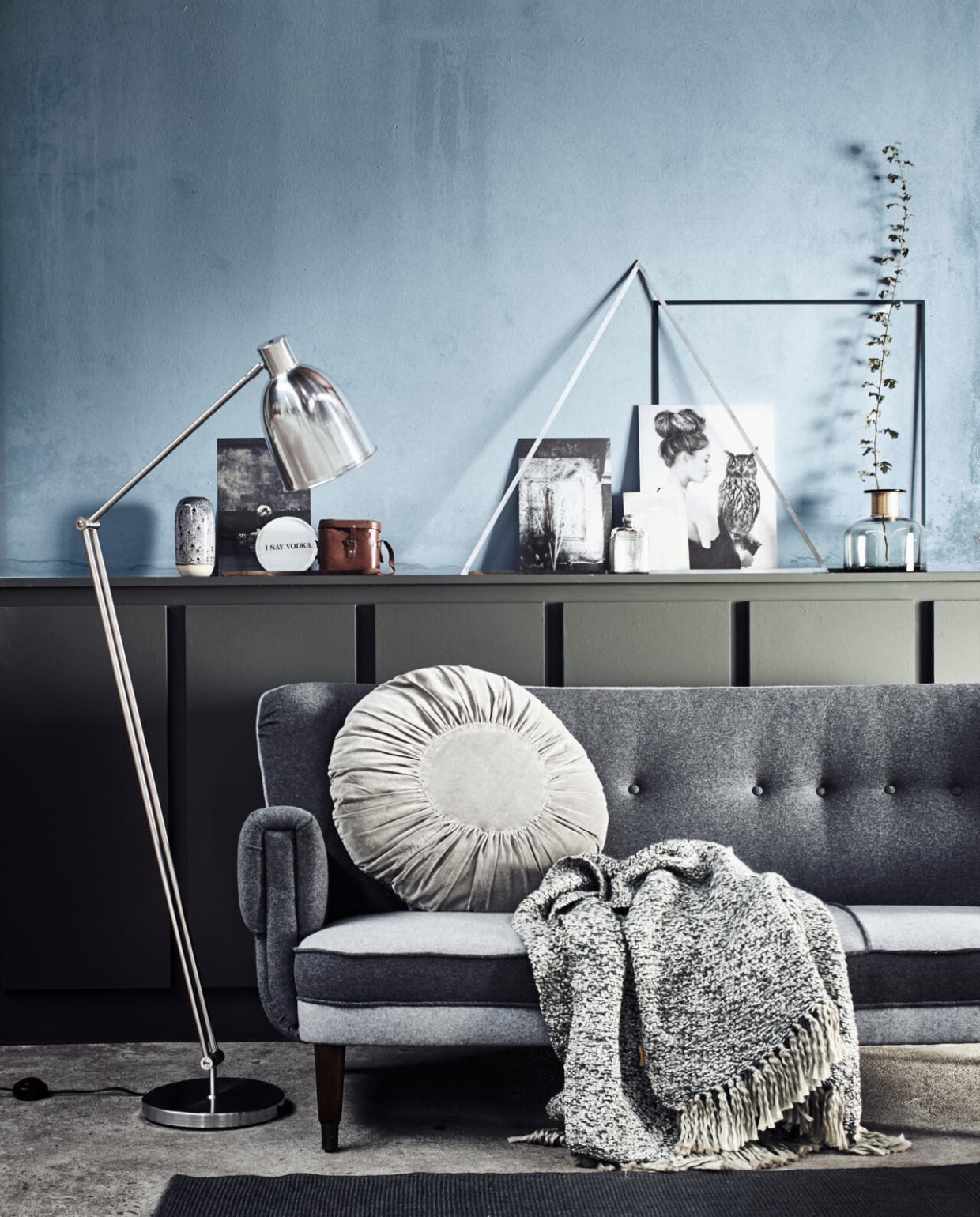 vtwonen collectie (lamp Comet aluminium, 150x18,5 cm (hxØ).) De Machinekamer (bank), Six and Sons (vloerkleed, linker vaas), Madam Stoltz (kussen), De Weldaad (plaid), Burbri (bruin leren tasje, zilverkleurige zakfles), Couleur Locale (zwart-wit foto's uit de LW Mood Board Portfolio No 2 van Hannah Lemholt), Menu (vierkant en driehoekig metalen ornament), Nordal (grijze glazen vaas), Anna + Nina (bord met tekst), vtwonen (op de muur: kleur Old Blue, lambrisering in kleur Pine). vtwonen 11-2016 | Styling Cleo Scheulderman | Fotografie Jeroen van der Spek
