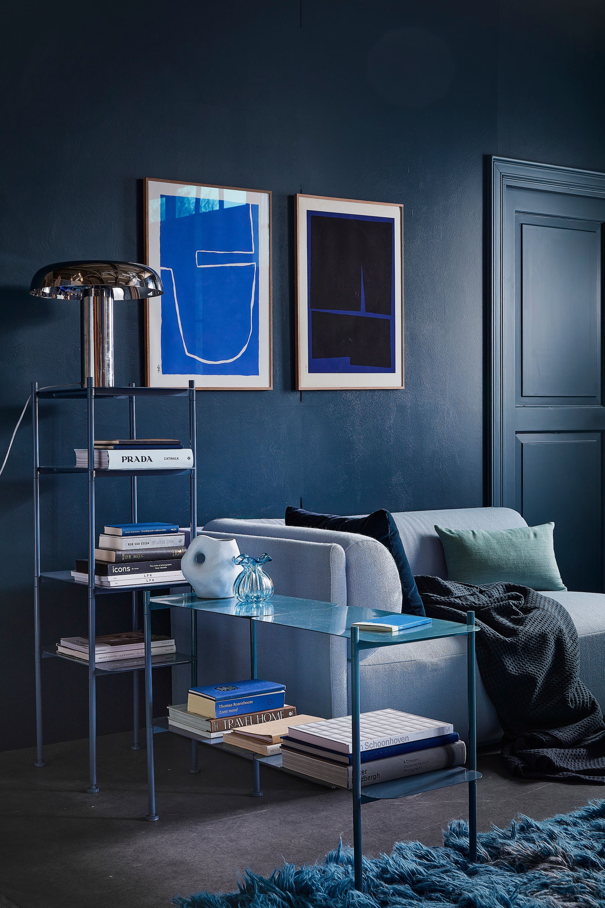 Muurverf en houtverf Steel Blue (pure-original.com). Bank Bolster longchair in kleur Vidar 723 (festamsterdam.com). Boekenkasten River in Ocean Blue(zuiver.com). Tafellamp Mushroom, vloerkleed Rough Waters, 170x280 cm (hkliving.com). Plaid van Vandyck, donkerblauw kussen van Hay (vtwonen.nl). Organische vaas van Madam Stoltz, glazen vaas Kataja van Nordal, zijden kussen van Urban Nature Culture, 50x30 cm (deens.nl). Boek van Prada (zarahome.com). Art print links The Route van Leise Dich Abrahamsen, 50x70 cm, art print rechts Blue Geometric 02 van Bycdesign Studio, 50x70 cm (theposterclub.com). Overig privébezit. vtwonen 01-2023 | styling Marlies Does | fotografie Peggy Janssen | decor Studio Milo