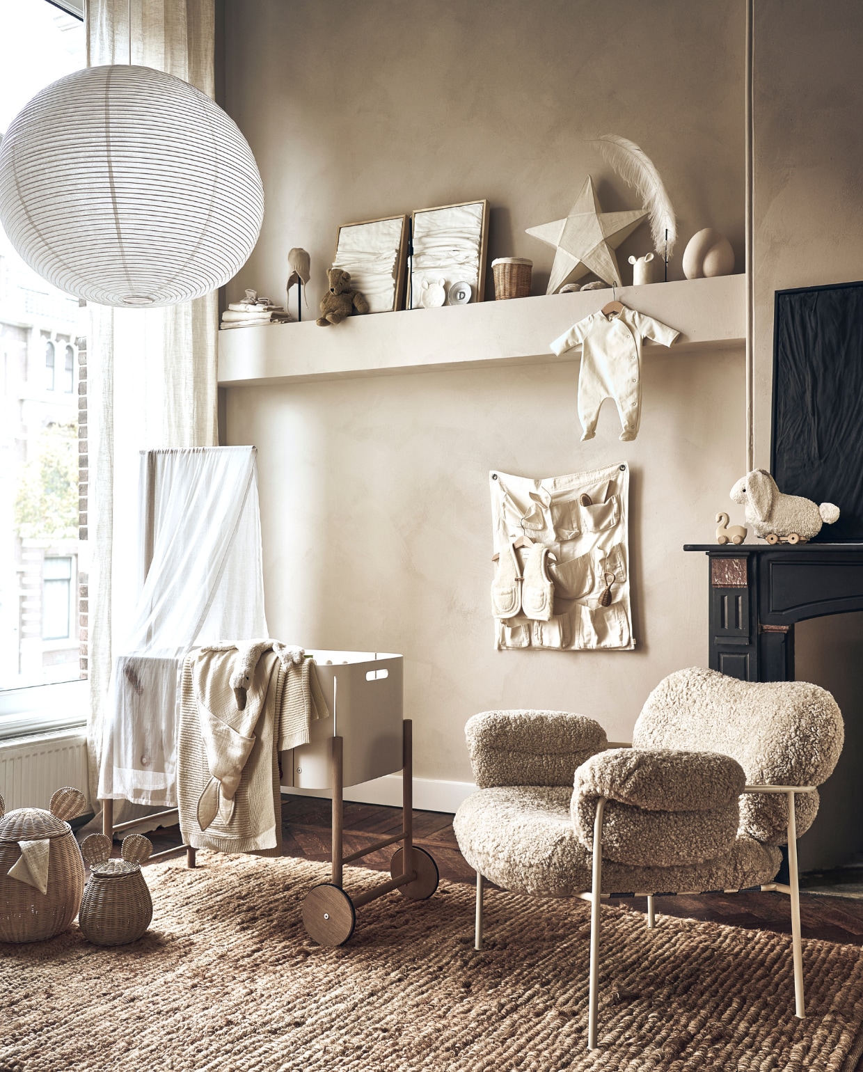Grote lamp van Hay (loods5.nl). Babybed, beige deken, pittenzak gans, handdoek konijn, lakens, beige sloffen, beige muts, knuffelbeer, bord met letter D van Anouk Kramer, extra small, witte sterlamp, babysloffen met schapenvacht, wit babypakje, houten zwaan, wit konijn met touwtje, witte vakkenzak, witte bodywarmer, konijnenbijtring (thearchivestore.com). Rieten mand op plank, rieten manden met oor, groot en klein, wit bord met oren, wit bakje met oren, rieten rammelaar, kam (zarahome.com). Witte kunst drieluik Triptych Water &amp; Air, 30x40 cm, zwart kunstwerk Water &amp; Cracked Mud, 60x80 cm (studio-harte.com). Veer op staander (taxidermy.nl). Sierbol op plank (eijerkamp.nl). Beige stoel met witte poten (homestede.nl). Muurverf onbekend. Overig privébezit. vtwonen 01-2023 | styling Liza Wassenaar | fotografie Sjoerd Eickmans