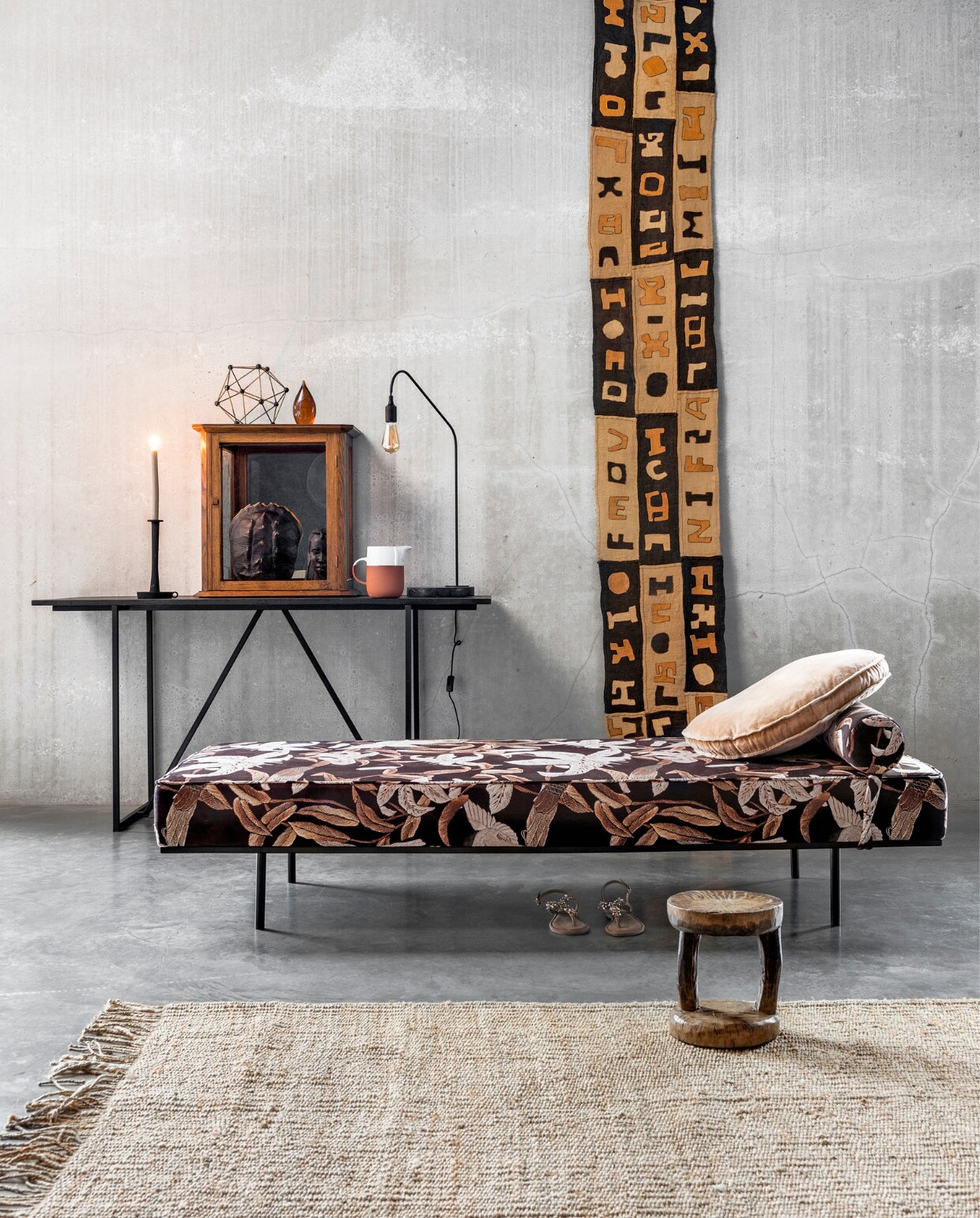 Daybed, 200x80x41 cm (lxbxh), rond kussen, vloerkleed van jute, 200x300 cm, steenoranje glazen presse-papier, object moleculair, kunst schildpadschild (HK Living). Wandtafel, 160x60x80 cm (lxbxh), lamp met marmeren onderstel (Nettie de Groot). Kandelaar (vtwonen.be). Kan van terracotta met wit glazuur (By Mölle). Vitrinekastje (De Weldaad). Wandkleed van oude Kuba borduursels (ML Fabrics). Houten Batonga kruk (Couleur Locale). Sandalen (Tamaris). vtwonen 02-2018 | Styling Marianne Luning | Fotografie Stan Koolen
