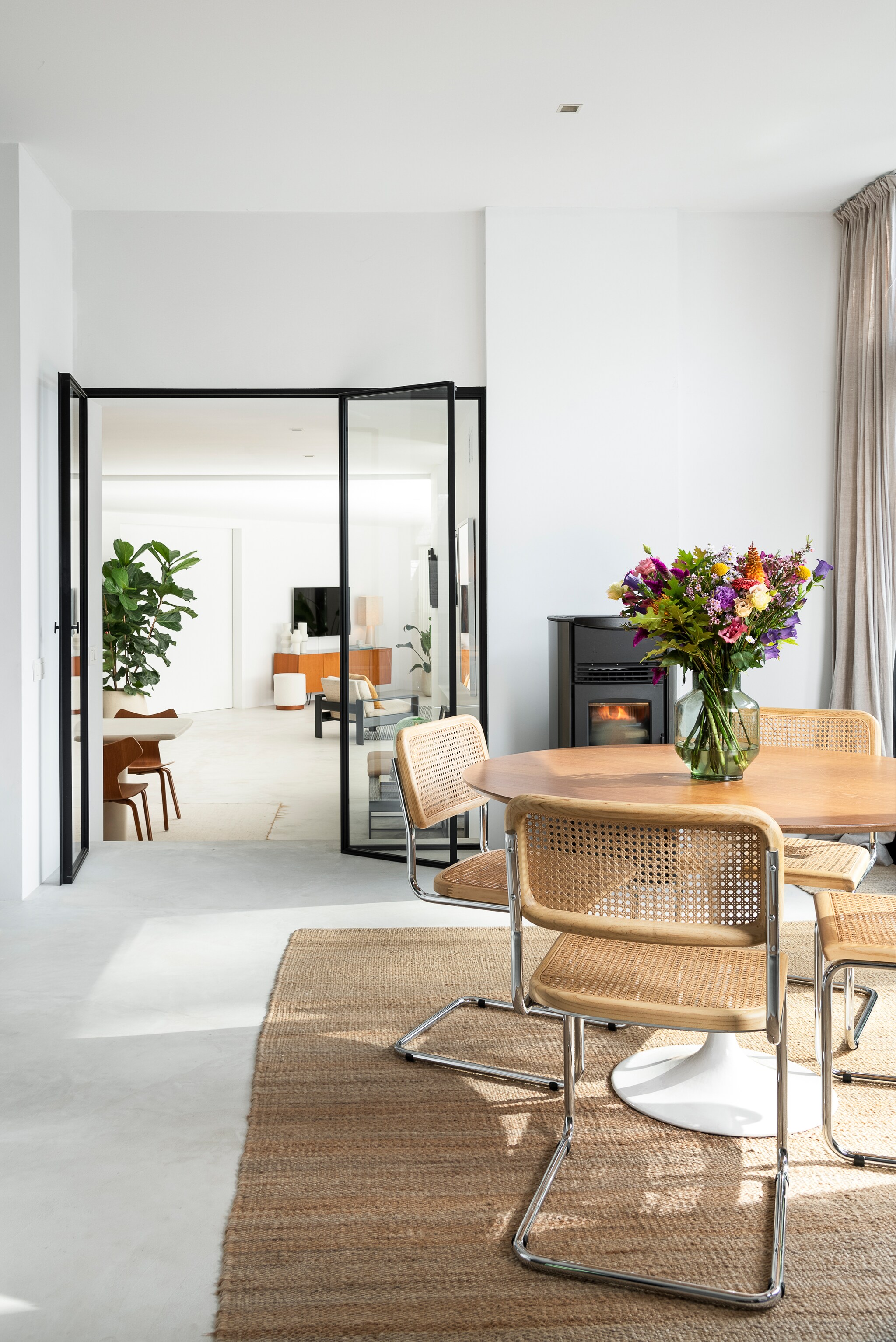 Vloer Terra Logica van Terra International. Stoelen Swing en vloerkleed Killia van Furnified. Vintage tafel Brussels Design Market. Vaas HKliving. Pelletkachel Superior Stufe. Deuren op maat gemaakt Philip V. Achter de deuren eettafel Pim en dressoir Pisa van Furnified, vazen House Doctor, tafellamp HKliving, fauteuil vintage. vtwonen 05-2023 | fotografie Jonah Samyn | tekst Katrien Depoorter