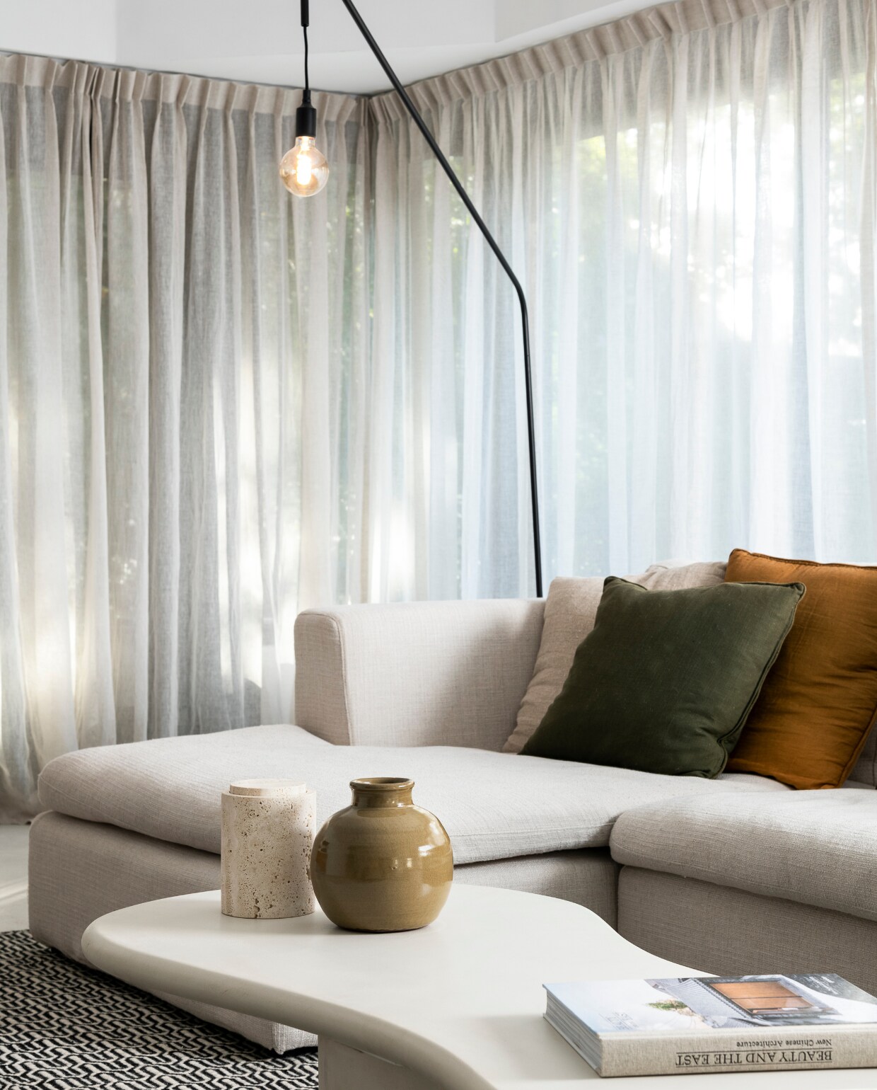 Hoekbank Modular, salontafel Orleans, vloerkleed Helder, vloerlamp Ellis en vaas op salontafel van Furnified. Kelimkussens Urban Nature Culture. Gordijnen Echt Gordijn. Overig onbekend. vtwonen 05-2023 | fotografie Jonah Samyn | tekst Katrien Depoorter