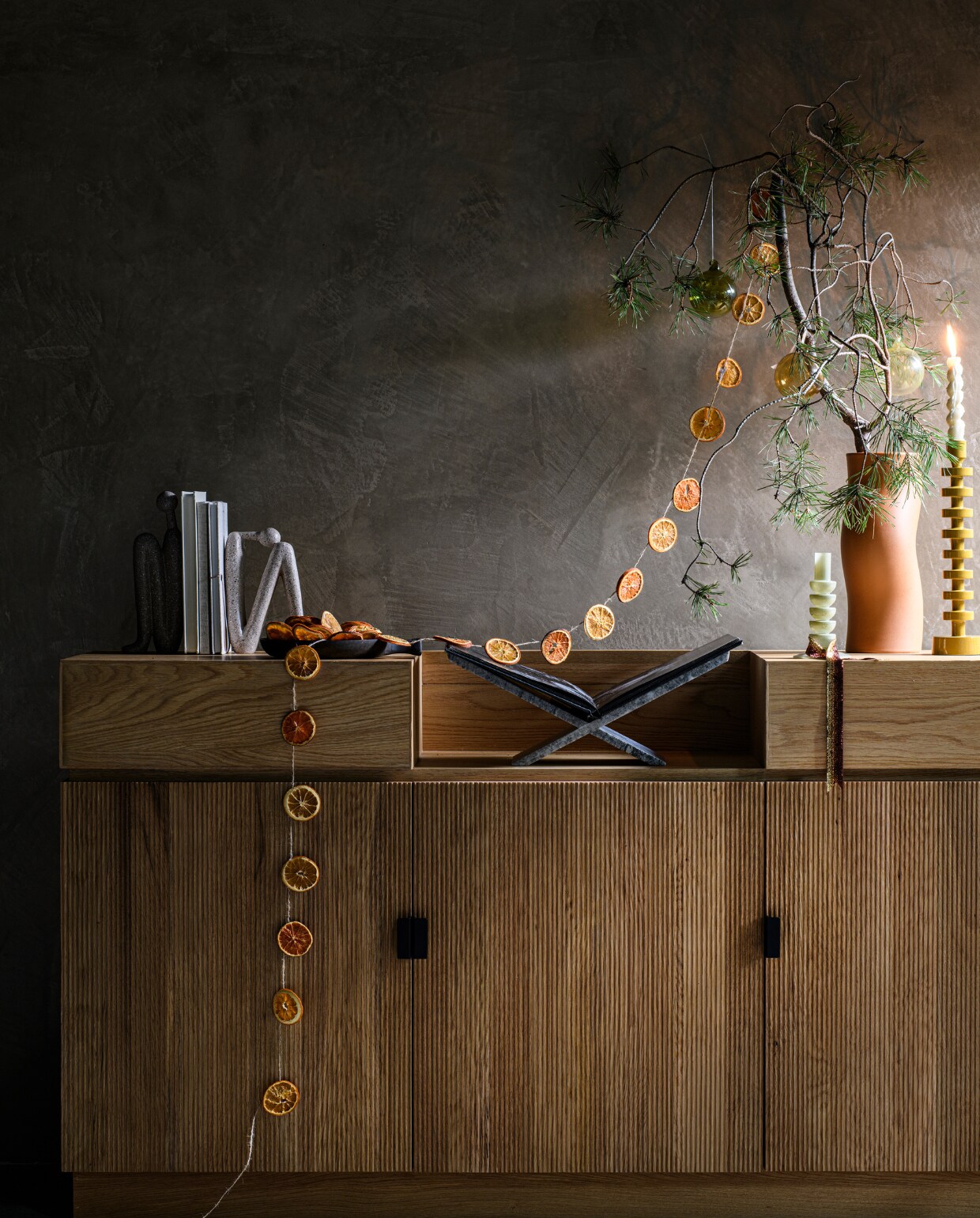 Eiken dressoir Pigalle uit de eigen collectie van Loods 5, 160x45x86 cm (bxdxh) € 1495,- (loods5.nl). Zwarte mangohouten schaal van vtwonen, S € 12,95 en L € 14,95 (vtwonen.be/shop). Terra aardewerken vaas Lien € 14,99, oranjebruin velours lint vanaf € 1,99 (intratuin.nl). Wandafwerking marmerlook Coristil, prijs op aanvraag (viaestudio.nl). In tak: olijfgroene en smoked mondgeblazen kerstballen, per 4 € 25,- (fermliving.com). Overig privébezit. vtwonen bijlage kerst 2023 | styling Marit Saladini | fotografie Louis lemaire