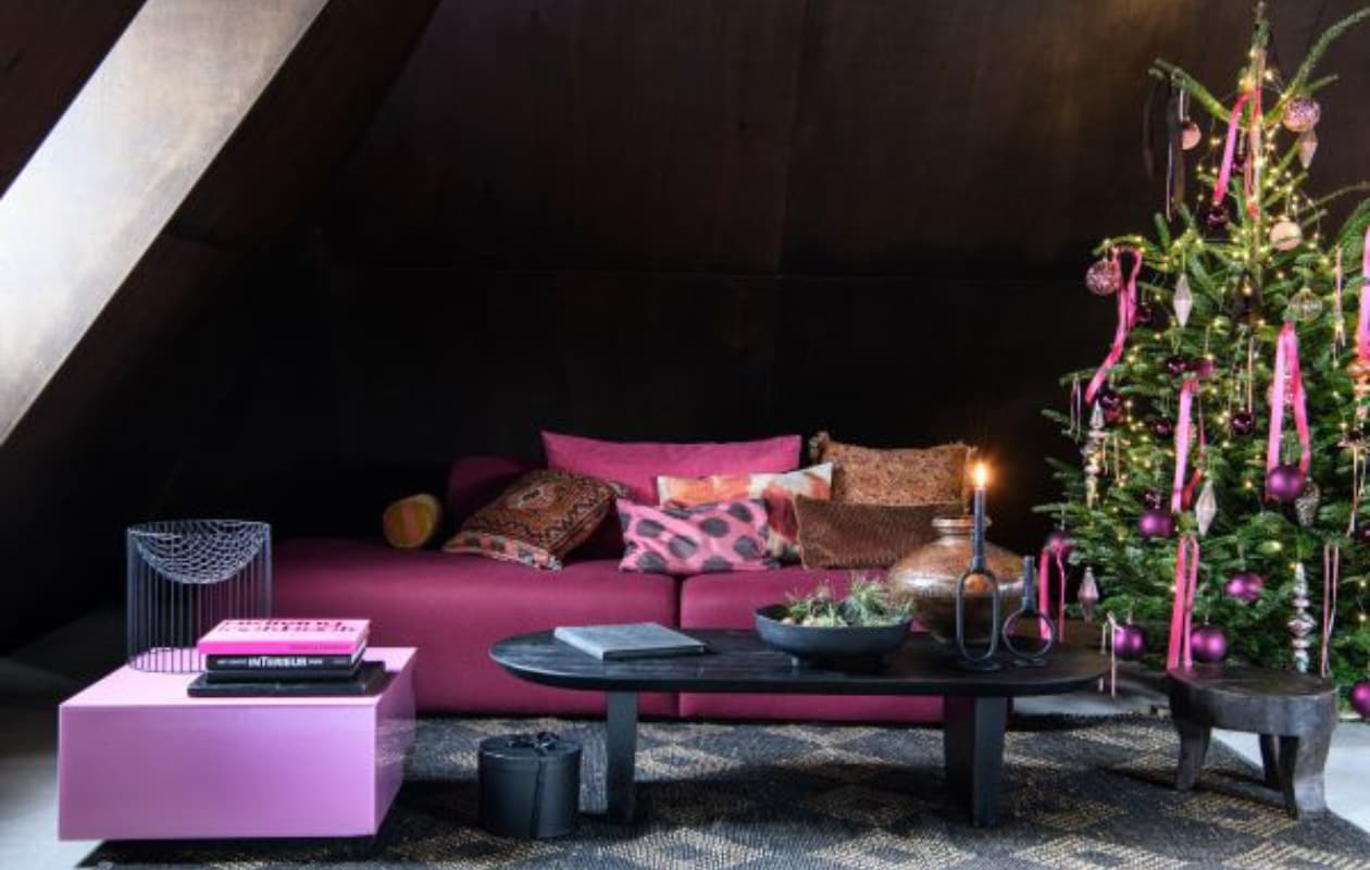 Roze salontafel Mirror Block van HKliving, 60x60x32 cm (bxdxh) € 349,- (vtwonen.be/shop). Vloerkleed Diamant van HKliving, jute en zacht katoen, 240x150 cm € 374,- (dotshop.nl). Zwarte mangohouten salontafel Bullnose, 140x60x35 cm (lxbxh) € 609,-, koperen oude waterpot € 360,-, zwarte kruk Tribal € 204,- (rawmaterials.eu). Zwarte schaal Plateau Paper uit eigen collectie van Loods 5 € 29,95 (loods5.nl). Zwarte stenen kandelaar Bobbi, klein € 9,99 en groot € 14,95 (thingsilikethingsilove.com). Modulaire sofa Mags, in stof Divina Melange 3 by Kvadrat, kleurcode 620, 256x135,5x67 cm (bxdxh) vanaf € 3150,- (hay.nl). Kussens gemaakt van reststof (markt). Perzisch tapijtkussen (marktplaats.nl). Gebloemd kussen van Madam Stoltz € 18,- (deens.nl). Frambozen satijnlint, rol 32 meter € 3,49 (lintenkopen.nl). Framboosroze kunststof kerstballen, 10 cm (Ø), set van 4 € 14,24 (blokker.nl). Glazen piek Pennystone € 12,99, overige kerstballen vanaf € 1,99 (intratuin.nl). Overig privébezit. vtwonen bijlage kerst 2023 | styling Marit Saladini | fotografie Louis lemaire