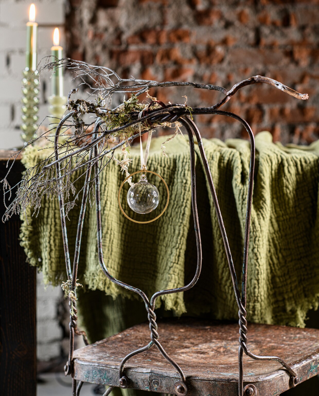 Vintage stoel India € 159,- (rawmaterials.eu). Mosgroene plaid Jet uit eigen collectie van Loods 5, 170x130 cm € 39,95, beige kandelaar van melkglas Fem uit eigen collectie van Loods 5, 16,5 cm (h) € 9,95 en 30 cm (h) € 12,95 (loods5.nl). Glazen kerstballen Smoke Kitai in metalen ring, set van 4 € 54,95 (blomus.com). vtwonen bijlage kerst 2023 | styling Marit Saladini | fotografie Louis lemaire