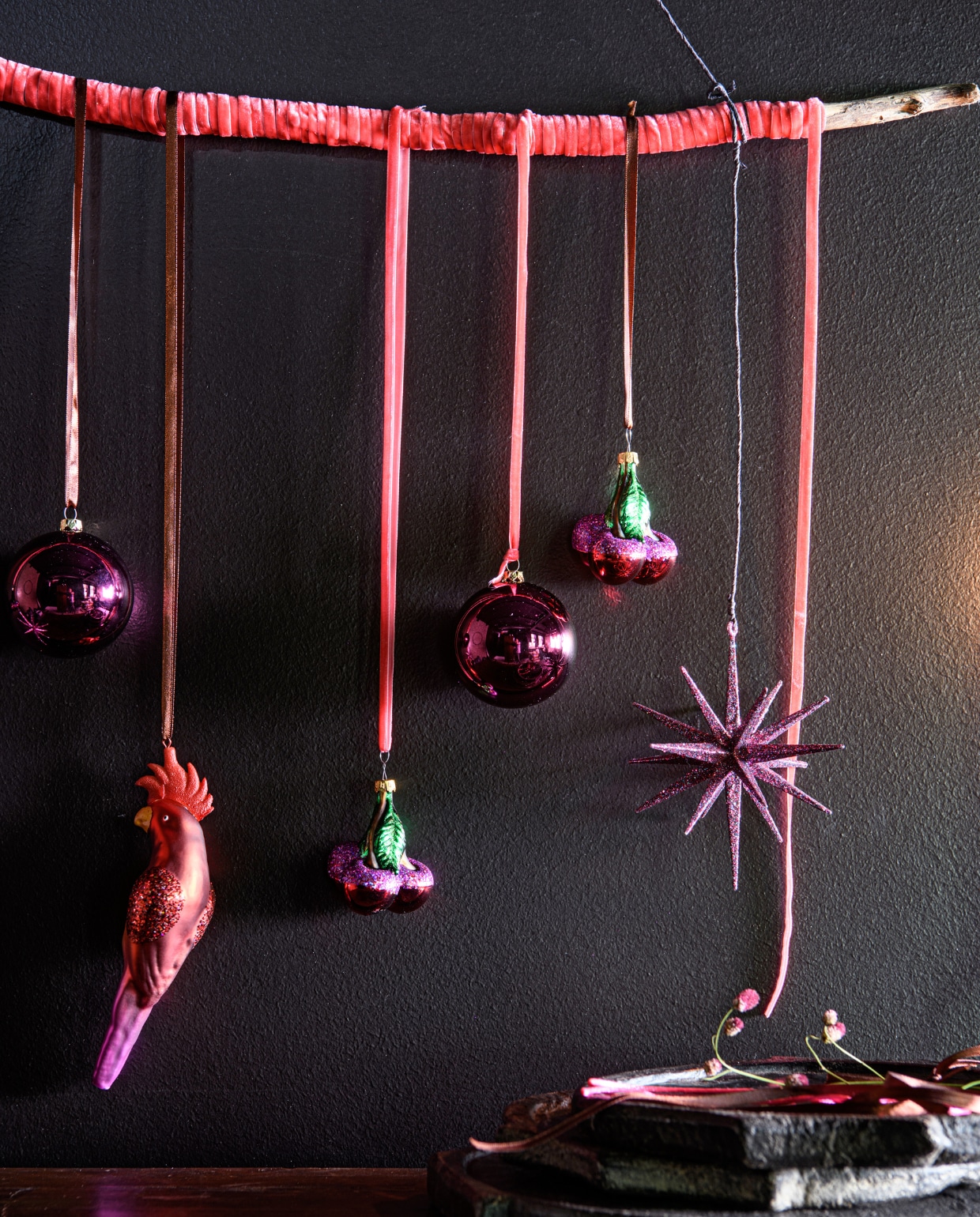 v.l.n.r. velours lint roze 5 mm per rol vanaf € 1,99 (intratuin.nl). Framboos kunststof roze ronde kerstballen, glans/mat, per 20 stuks € 13,- (blokker.nl). Glazen ornament papegaai vanaf € 2,99, roze/groen ornament kers vanaf € 2,99, glitter ster ornament vanaf € 2,99 (intratuin.nl). vtwonen bijlage kerst 2023 | styling Marit Saladini | fotografie Louis lemaire