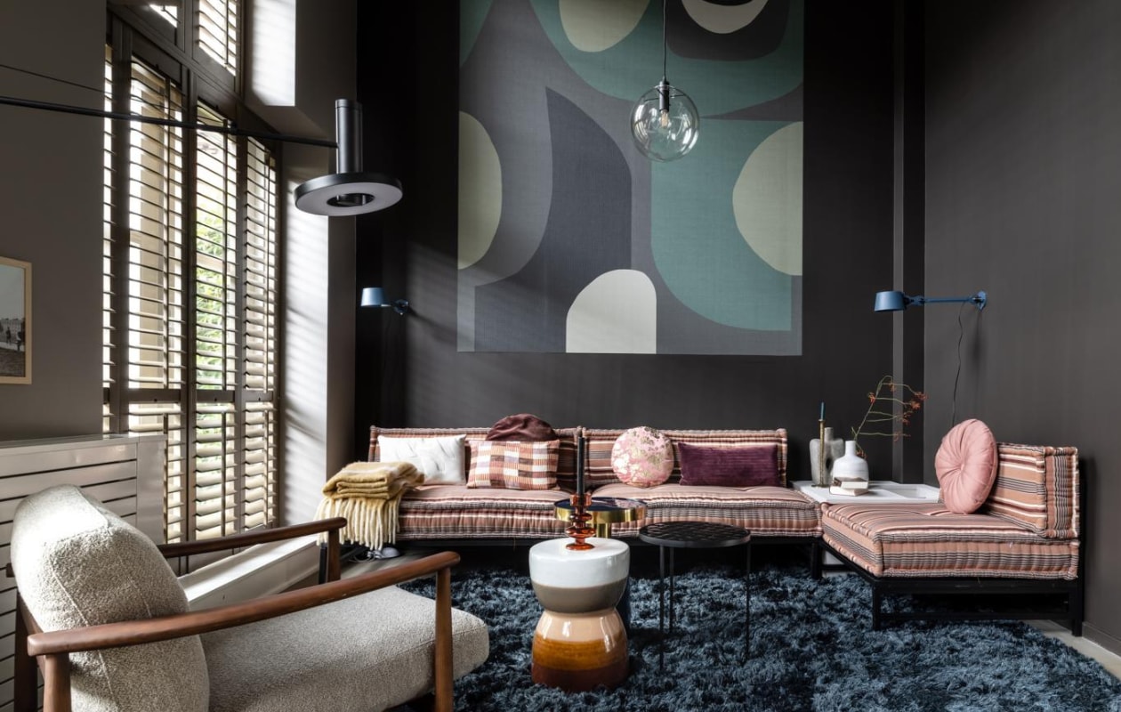 Flexa Easycare Muren muurverf bij eethoek Boomschorsbruin, bij zithoek Fading Horizon (flexa.nl). Op maat gemaakte shutters kleur Rustic Grey (jasnoshutters.nl). Elementenhoekbank van kussens, metalen frame (householdhardware.nl). Fauteuil Todd van Pols Potten, op maat gemaakt vloerkleed Arezzo (eijerkamp.nl). Blauwe bijzettafel Glam, zwarte bijzettafel Glazed (zuiver.com). Keramische kruk Glazed van BePureHome, waxinelichthouder Intuitive Arabian Spice van Urban Nature Culture, kussens, boven eettafel hanglamp Walnut van ETH, glazen vaas van HKliving, retro vaas op tafel van HKliving (vtwonen.nl). Op DIY-hoektafel kaarsenstandaard Antique brass van BePureHome, vaas Cubist van BePureHome, op bank plaid Ice Cream (basiclabel.nl). Zwarte wandlamp Beads wall 120 (tonone.com). Hanglamp Warsaw (itsaboutromi.nl). Eettafel Sunday van Xooon (eijerkamp.nl). Eetkamerstoelen Albert Kuip Coffee (zuiver.com). Trap bekleed met decor Mountain Oak met stootborden in kleur Sand, (upstairs.nl). Takken in vazen (plantje.nl). Overig privébezit. vtwonen weer verliefd op je huis seizoen 15, aflevering 9 | styling Fietje Bruijn | fotografie Sonja Velda