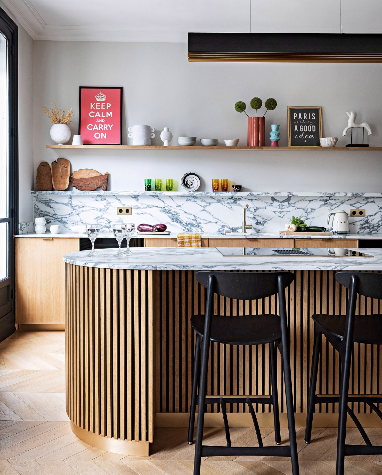 Keuken zelf ontworpen met marmer Arabescato Corchia van Spadaccini, op maat gemaakt door Ceramica. Barstoelen Timber Black van 366 Concept, hanglamp Respiro van Dcw Éditions, houten snijplanken Monoprix. Gekleurde glazen, wit servies en beeld vlooienmarkt. Wijnglazen Christofle, koperkleurige vaas India Mahdavi, lichtschakelaars Modelec. Overig onbekend. vtwonen 12-2023 | productie AC Scoffoni | styling Marie-Maud Levron | fotografie Yann Deret | tekstbewerking Merel van der Lande