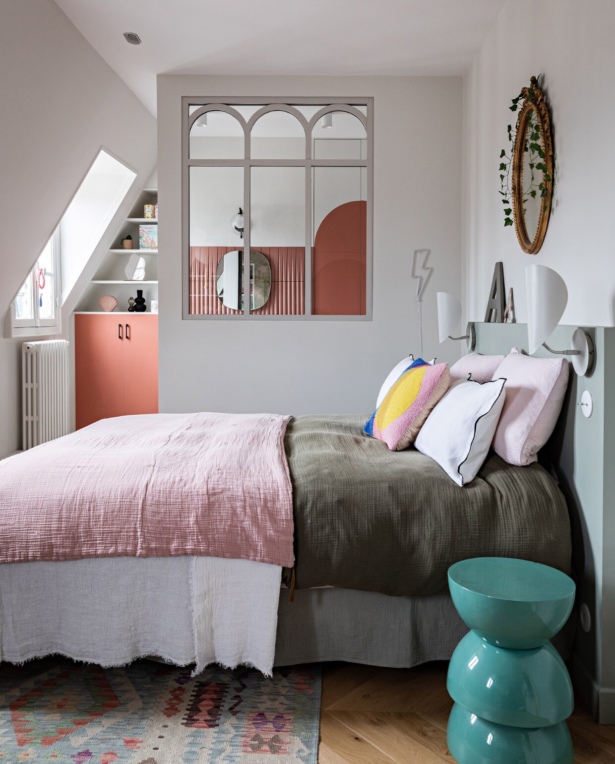 Spiegel boven bed erfstuk, vloerkleed Kilims Ada. Beddengoed La Redoute en Numero 74. Bedlampen Am.pm. Wandlamp bliksemflits en bed La Redoute, bijzettafel India Mahdavi, radiator Acova. Tussenraam ontworpen door Anne, gemaakt door Claustra. Verf hoofdbord Green Blue, verf kast en deur Red Earth van Farrow &amp; Ball. Overig onbekend. vtwonen 12-2023 | productie AC Scoffoni | styling Marie-Maud Levron | fotografie Yann Deret