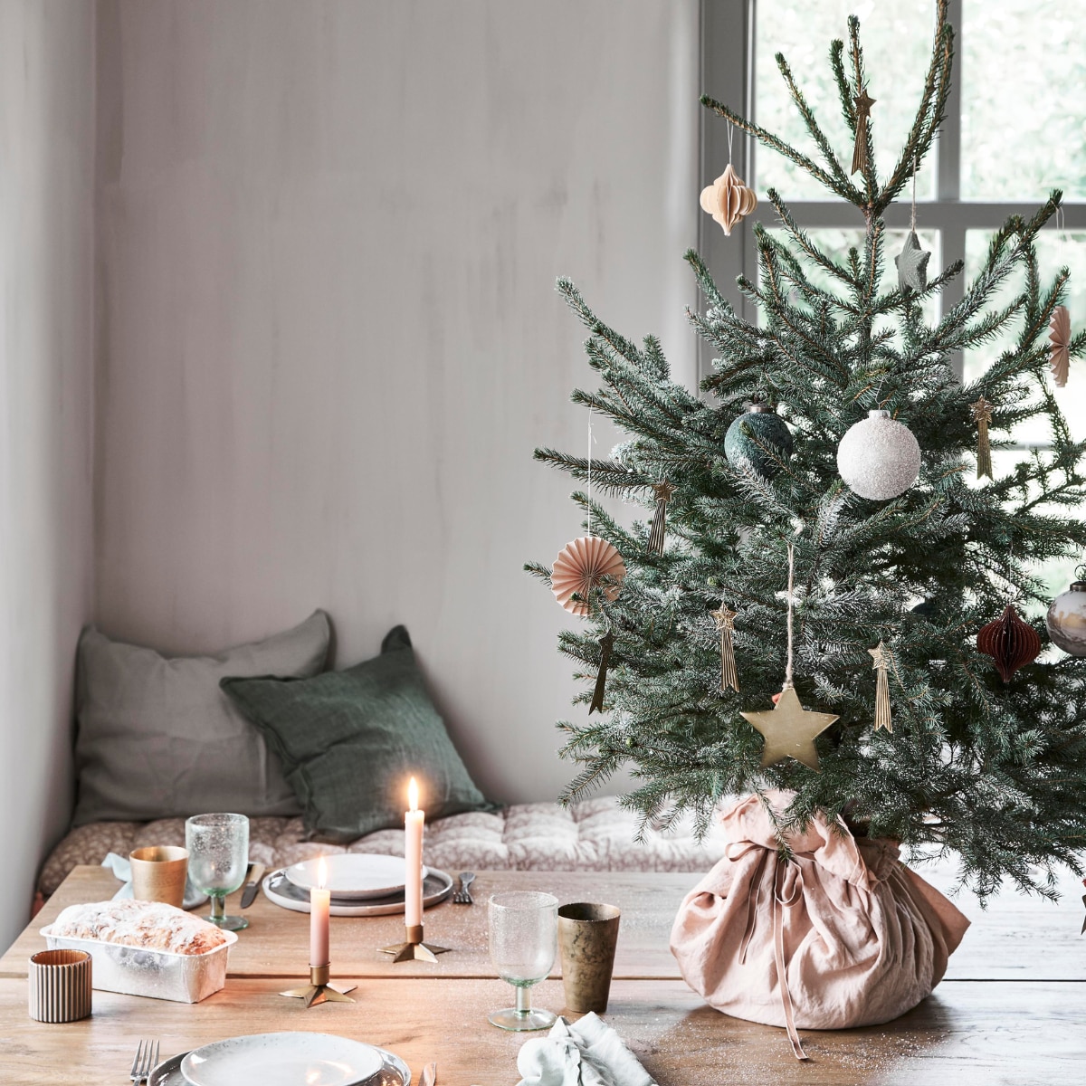 In de boom: papieren waaier, groene bal, bal met sneeuw, groene ster, honeycomb ornament (intratuin.nl). Messing vallende sterren (weldaad.com). Grote messing ster van Madam Stoltz (deens.nl). Op tafel: servet (sostrenegrene.com), waxinelichthouder (intratuin.nl). Messing beker, kandelaar in stervorm (weldaad.com). Groen wijnglas van Nordal (deens.nl). Zitkussen Nisha rose 50x155 cm (lxb), groen kussen van Bungalow 50x50 cm (scandicliving.nl). Zachtgroene kussensloop 50x60 cm (yumeko.nl). vtwonen kerstbijlage 12-2020 | styling Marlies Does | fotografie Bart Brussee