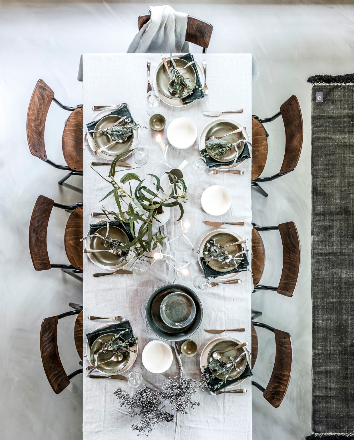 Tafel Olsen van Braxton, 220x90 cm, stoelen Scuola van Dutchbone, grote witte borden van Walra per 2, olijfgroene borden Surface van Serax, witte schaaltjes van Walra per 2, kleine olijfgroene schaaltjes Surface van Serax, witte karaffen van Royal Doulton (vtwonen.nl). Bestek Behagfull 24-delig, wijnglazen Hederlig (Ikea). Grote grijze schaal, kleinere grijze schalen (In-Petto). Kandelaars van K’willem (Loft). Donkergroene linnen servetten, lichtgrijs linnen tafelkleed, tafelkleed over de stoel (MrsBloom). Een dadeltak van een bloemist is zilver gespoten met spuitlak (Hema). vtwonen 12-2017 | styling Moniek Visser | fotografie Sjoerd Eickmans