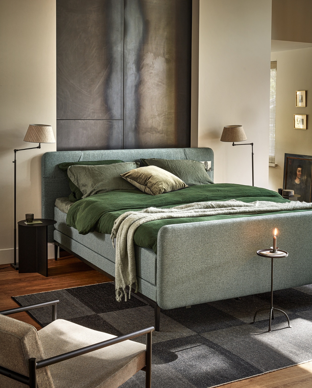 Boxspring Lifestyle by vtwonen Basil, hier in 180x210 cm, vanaf  € 1990,-, hier uitgevoerd met hoofdbord met opbergvakken voor tijdschriften of mobiele telefoon, in stof Tweed Sea Green, met metalen poot Angle in zwart.M.m.v. vtwonen.nl (fauteuil van Serax, metalen bijzettafel van Hay, geblokt vloerkleed van Hay) hm.com (donkergroen mousseline dekbedovertrek, groen linnen kussenslopen, groen linnen laken, fluwelen kussenhoes, wollen plaid) zarahome.com (klassieke bijzettafel van staal). Overig privébezit. vtwonen 13-2023 | productie Tanja Saarberg | styling Sanne Ketelaar | fotografie Peggy Janssen