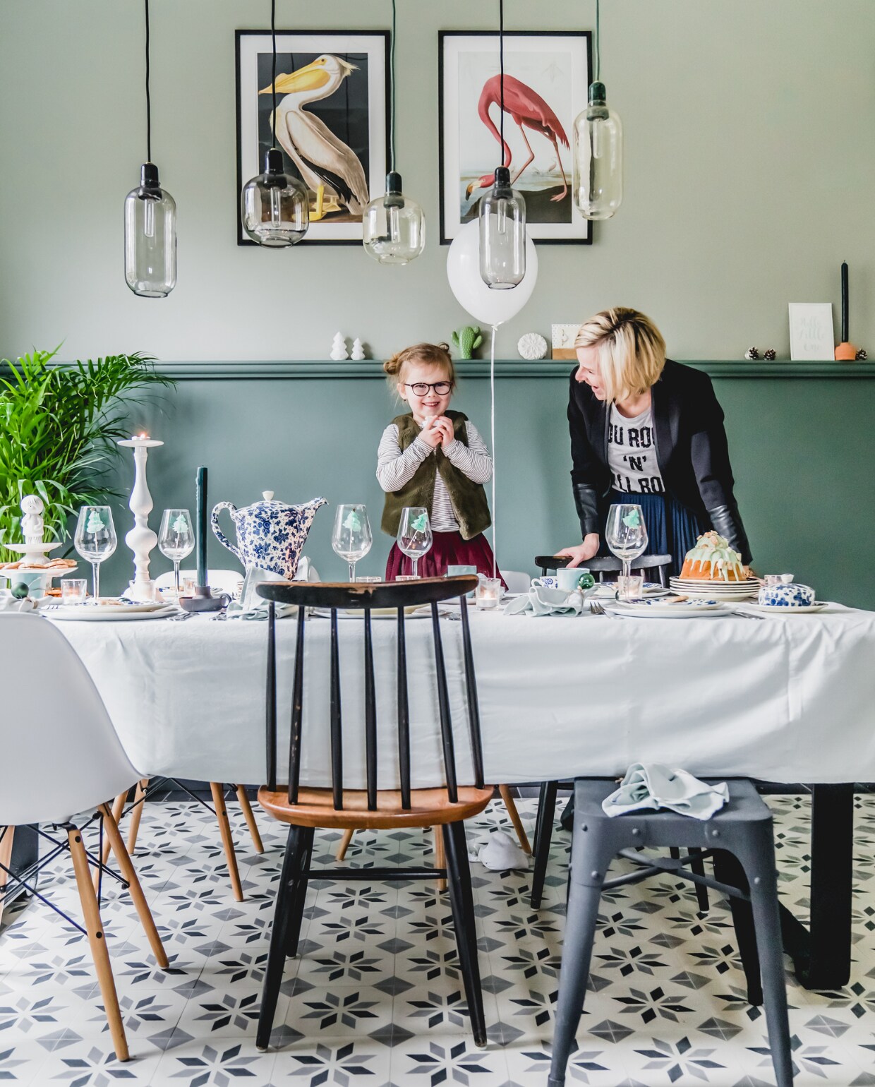 Soof en Marjolein versieren de eetkamer. Op de vloer liggen nieuwe Portugese cementtegels met een nostalgische uitstraling van Floorz. De eettafel is door de vader van Jankees gemaakt met een onderstel van de plaatselijke smid. Rond de tafel een mix en match van oude stoelen van Marjoleins oma en nieuwe stoelen van Vintage Lab. Posters via Junique, lampen van Normann Copenhagen. Kleurnaam verf onbekend. vtwonen 12-2019 | Productie Features &amp; More | Styling Wilma Custers | Fotografie Ivar Janssen