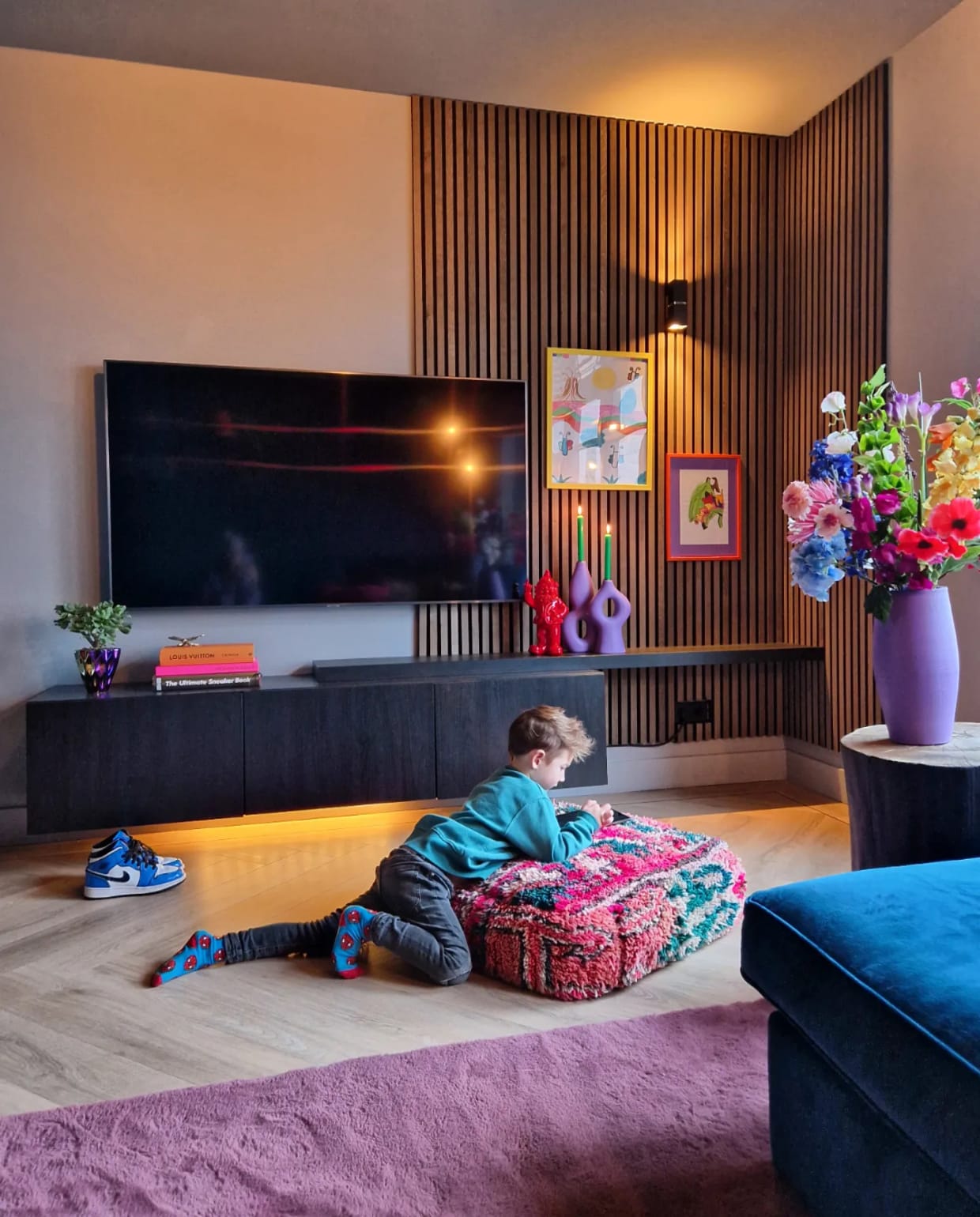Akoestische wandpanelen WoodUpp, tv-meubel Ikea, poef Living Maroc. Kandelaars Kwantum, geverfd. Vaas kringloop, geverfd. Wandlamp Lucide. Vloer walvisgraat van Floer, bank A-meubel. Overig onbekend. Fotografie Anne Marie Vandersteen