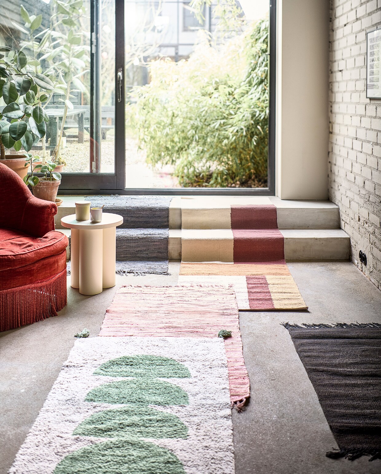 Roze en lichtgrijze vloerkleden Chindi van Bungalow, 60x90 cm, donkerbruin vloerkleed van Ferm Living, 60x100 cm, multicolour, handgeweven vloerkleed, 70x200 cm (deens.nl). Kruk Oly van Noo.Ma in kleur Piazza Beige (vtwonen.nl). Terracotta bloempotten en schotels in verschillende maten (intratuin.nl). Groen-witte katoenen loper met kwastjes van Madam Stoltz, 70x140 cm (deens.nl). vtwonen 04-2022 | styling Marlies Does | fotografie Sjoerd Eickmans