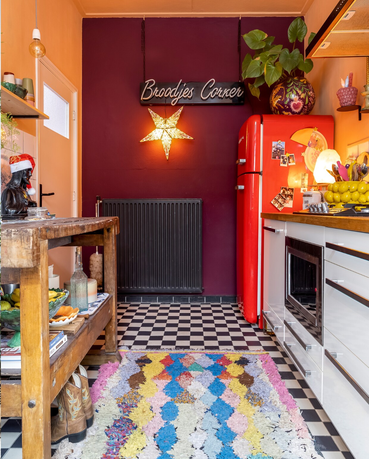 Jezusbeeld kringloopwinkel. Vloertegels Gamma. Kleed uit Marrakech. Keuken Ikea. Rode koelkast Smeg. Muurverf Bordeaux Leaf van Flexa. Verlichte ster Rok &amp; Billie. Bord Broodjes Corner vintage. Bloempot op koelkast zelf geschilderd. Frambozenpot Intratuin. Citroenschaal Des Pots. Overig onbekend. vtwonen 13-2023 | fotografie Henny van Belkom