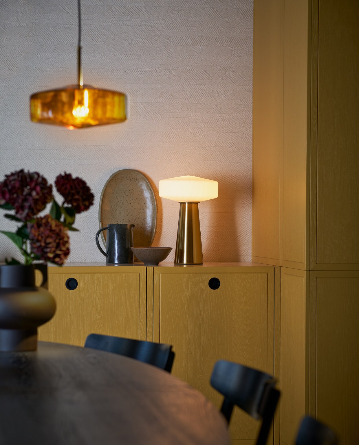 Hanglamp Pleat, helderbruin glas en goud metaal, 40x17 cm (Øxh) € 229,90. Ook verkrijgbaar in 30x17 cm (Øxh) € 159,90 en in matwit en helderwit glas. Tafellamp Pleat, matwit glas en goud metaal, 40x53 cm (Øxh) € 279,90. Ook verkrijgbaar in 30x45 cm (Øxh) € 229,90 en in helderwit en helderbruin glas.M.m.v. hm.com (vaas, schaal, kom). Overig privébezit. productie Tanja Saarberg | styling Cleo Scheulderman | fotografie Jeroen van der Spek