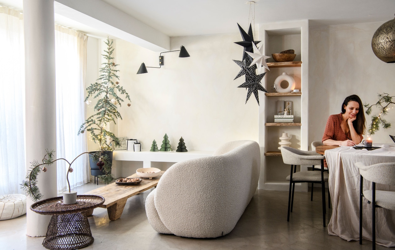 Vloer Tav Microcement, muurverf Fresco in Bone van Pure &amp; Original. Gordijnen Amphora 02 en eetkamerstoelen River van Dotshop. Driezitsbank Paul van Sofacompany. Salontafel Nagaland en schalen in kast Vanheesdesign. Gevlochten bijzettafel, zwarte schaal en zwart kaarsplateau Raw Materials. Zandkleurige schaal en zwart-witte kerststerren Loods 5. Poef Household Hardware, blauwe ceder Intratuin. Ornamenten, vazen en tafelkleed H&amp;M Home. Plantenpot Tuincentrum Osdorp, cadeaudozen verzameld. Uitvouwkerstbomen Hema en MrsBloom. Wandlamp en zwarte kerstster House Doctor. Doos met ingelegde droogbloem Loesje van Herp, tafel HKliving, hanglamp Ball Filigrain XXL van Zenza Home, kaars Casa. vtwonen 13-2023 | productie Insidehomepage | fotografie Louis Lemaire