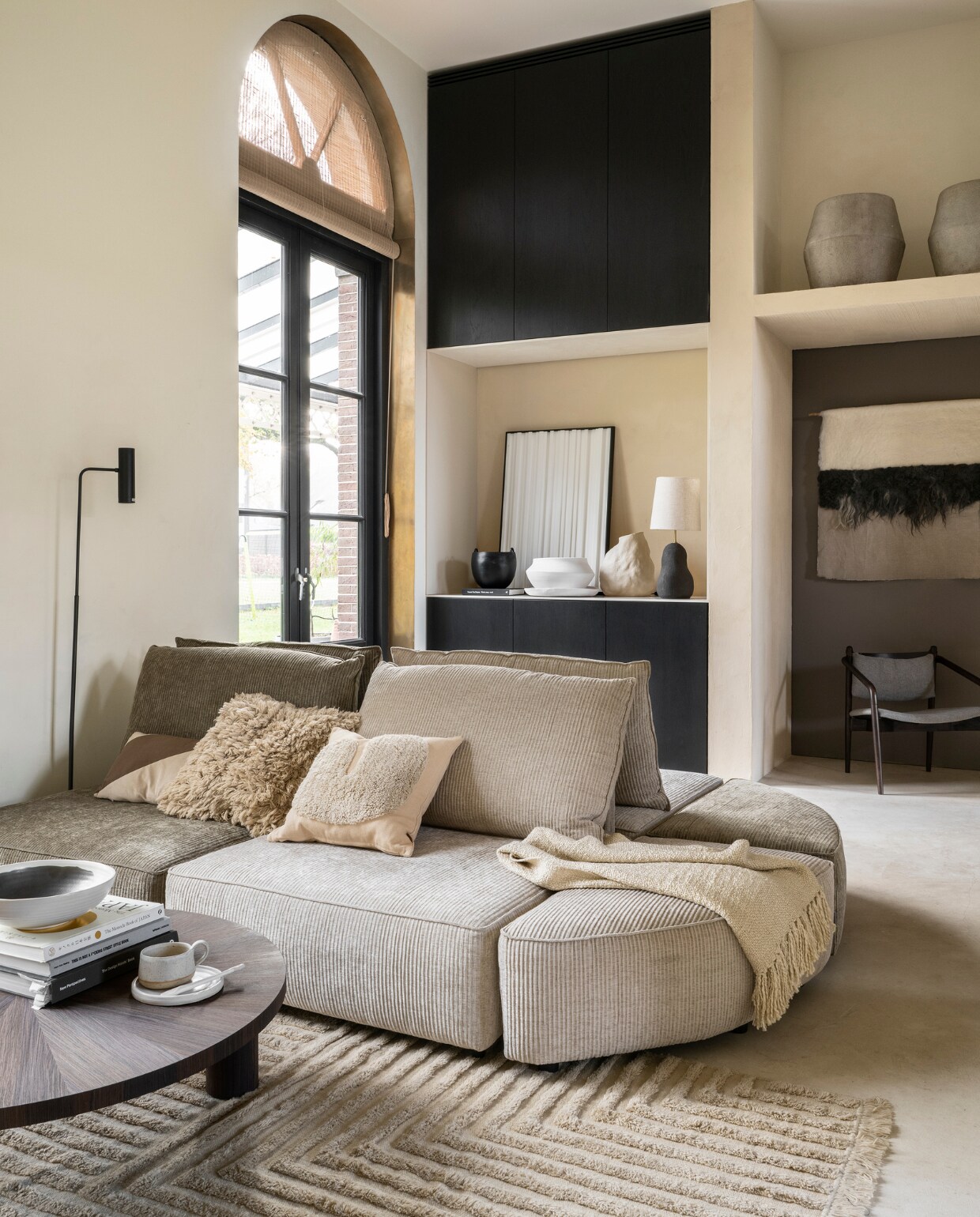 Stucco-look muurverf Mykonos (wearewowmakers.com). Duurzame bruine muurverf in kast Harbour no. 968 van Lab Paint (vestingh.nl). Ribfluwelen elementenbank Hunter (zuiver.com). Salontafel van Ferm Living, grote potten van Serax, schaal op salontafel van Ferm Living (flinders.nl). Vloerkleed van Ferm Living, hoogpolig kussen van Ferm Living, kussen met organische vorm van Ferm Living, kussen met diagonale streep Riley van Moos, plaid van Malagoon, zwarte vloerlamp van Bloomingville, stoel van Dutchbone(vtwonen.nl). Handgemaakt wandkleed van Babette Leertouwer, duurzame Nederlandse schapenwol en Belgisch linnen, 175x103 cm (halona.nl). Pot met oren, witte schaal, witte pot (urbannature- culture.com). Vaas organische vorm (loods5.nl). Tafellamp van Ferm Living (lampenmaster.nl). 3D-kunstwerk (studiolde.nl). Mok, schotel en lepel(studio-potterdam.com). vtwonen 03-2023 | styling Marianne Luning | fotografie Stan Koolen