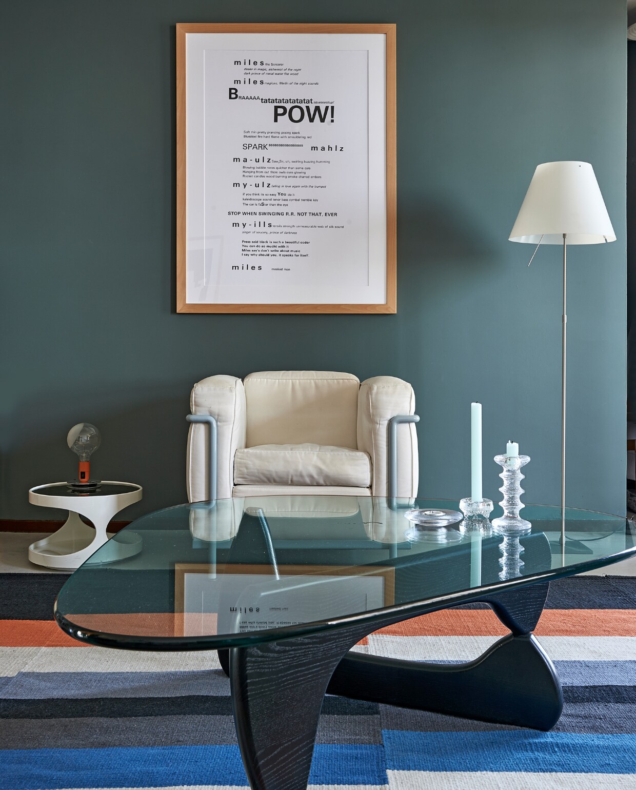 Fauteuil LC2 van Cassina, vloerlamp Costanza van Luceplan. Coffee Table van Isamu Noguchi (Vitra), kandelaars Iittala. Vloerkleed gemaakt van Ikea-lopers. Aan de muur een tekst over Miles Davis, het tafeltje kregen ze cadeau. Lamp Lampadina van Achille Castiglioni (Flos). vtwonen special binnenkijken 03-2020 | styling Rob Jansen | fotografie Dennis Brandsma