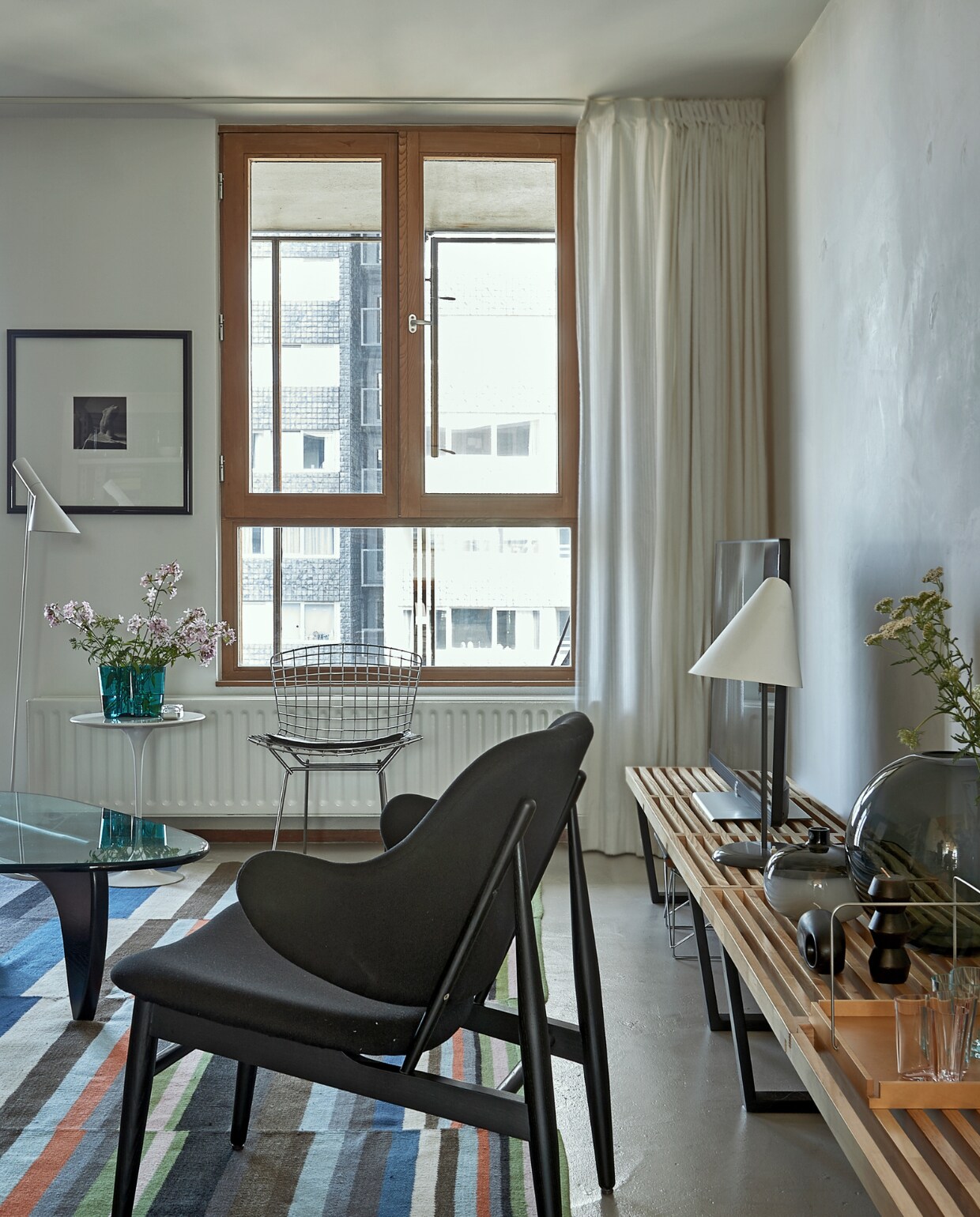 Houten Nelson bankjes Vitra. Tafellamp La Lune sous le Chapeau van Man Ray (Sirrah). Dienblad Driade, kaarsen en vazen kregen ze cadeau. Fauteuil van Ib Kofod Larsen. Draadstoel van Harry Bertoia voor Knoll. Kleed Ikea. vtwonen special binnenkijken 03-2020 | styling Rob Jansen | fotografie Dennis Brandsma