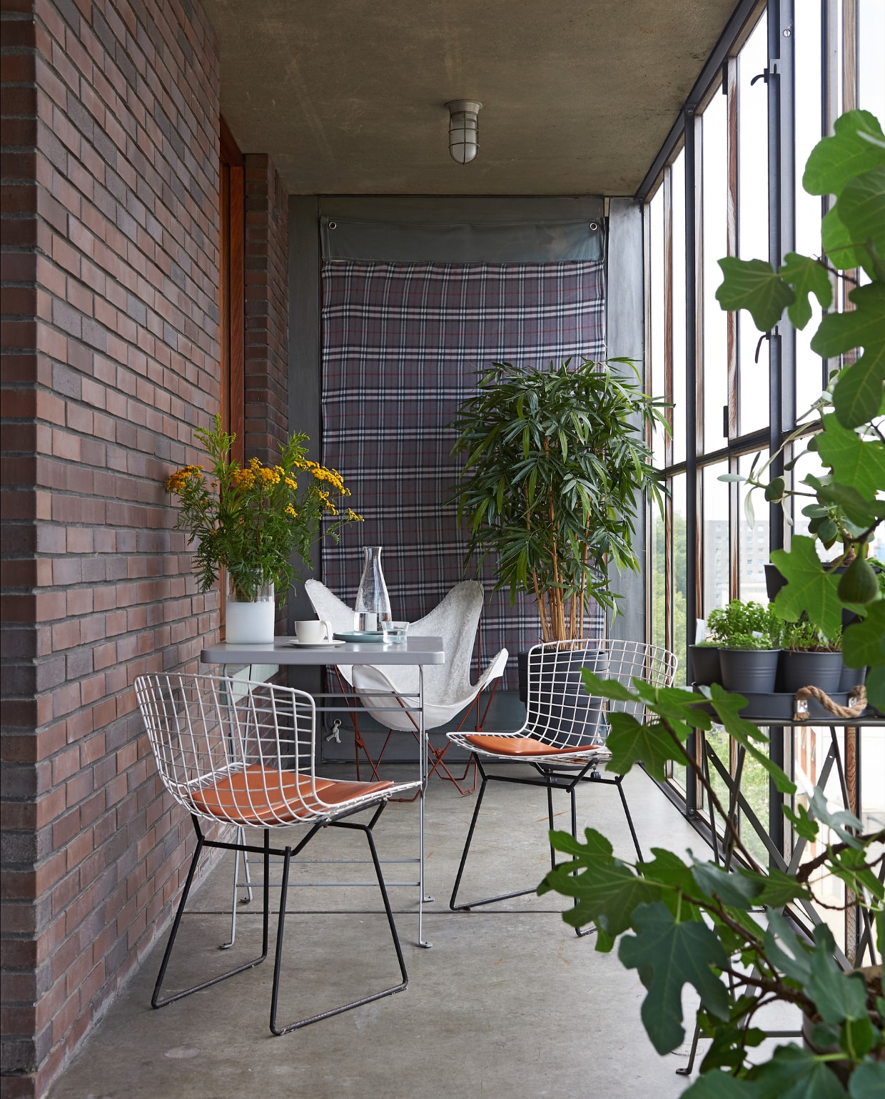 Balkon met uitzicht op het IJ. ‘In de zomer zitten we hier na vijven met een glaasje erbij heerlijk naar de bootjes te turen.’ Side chairs van Harry Bertoia (Knoll), vlinderstoel met witte vacht, tafeltjes Habitat. Aan de muur een plaid van Blokker vtwonen special binnenkijken 03-2020 | styling Rob Jansen | fotografie Dennis Brandsma