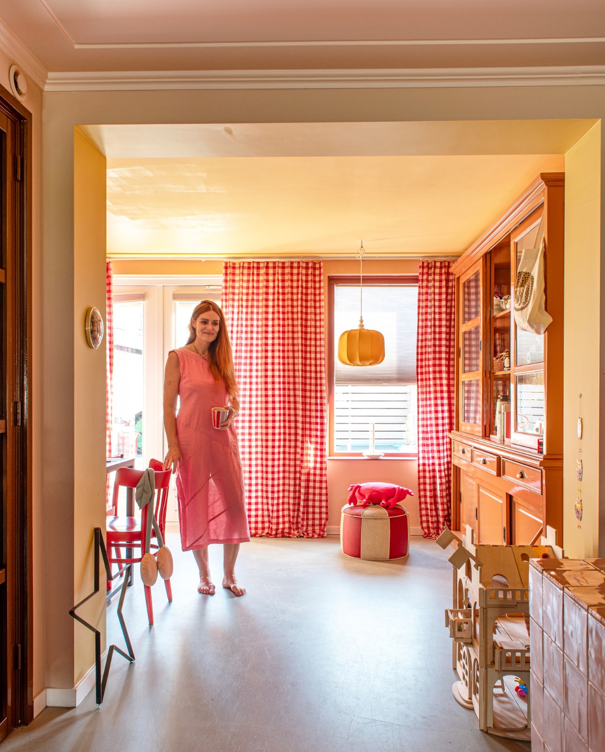 Vloer egaline, gele muurverf 70 Sunroom van Klint en roze muurverf Masquerade Mid van Little Greene. Gordijnen Svanefors van H&amp;M. Hanglamp en poef vintage. Buffetkast Het Kabinet, geschilderd, met behang van Swiet. Poppenhuis Lovelties, stoelen Hipstyling, hemel Play at Slaep, tafel zelfgemaakt en betegeld. Overig onbekend. vtwonen 01-2024 | styling Linda van der Ham | fotografie Caroline Coehorst