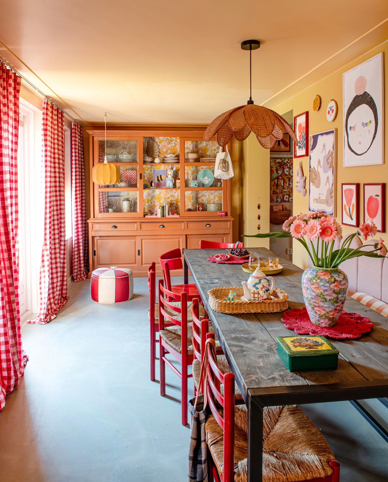 Muurverf 70 Sunroom van Klint. Vloer egaline, eettafel Stoer Metaal, achterwand met eetbank zelfgemaakt. Stoelen, poef en gele lamp vintage. Rotan lamp Leo and Moon. Buffetkast Het Kabinet, geschilderd, tegen de achterwand behang van Swiet. Gordijnen Svanefors van H&amp;M. Posters Atelier Florentine, Moozle, Wolfnoodle en Pansy. Overig onbekend. vtwonen 01-2024 | styling Linda van der Ham | fotografie Caroline Coehorst