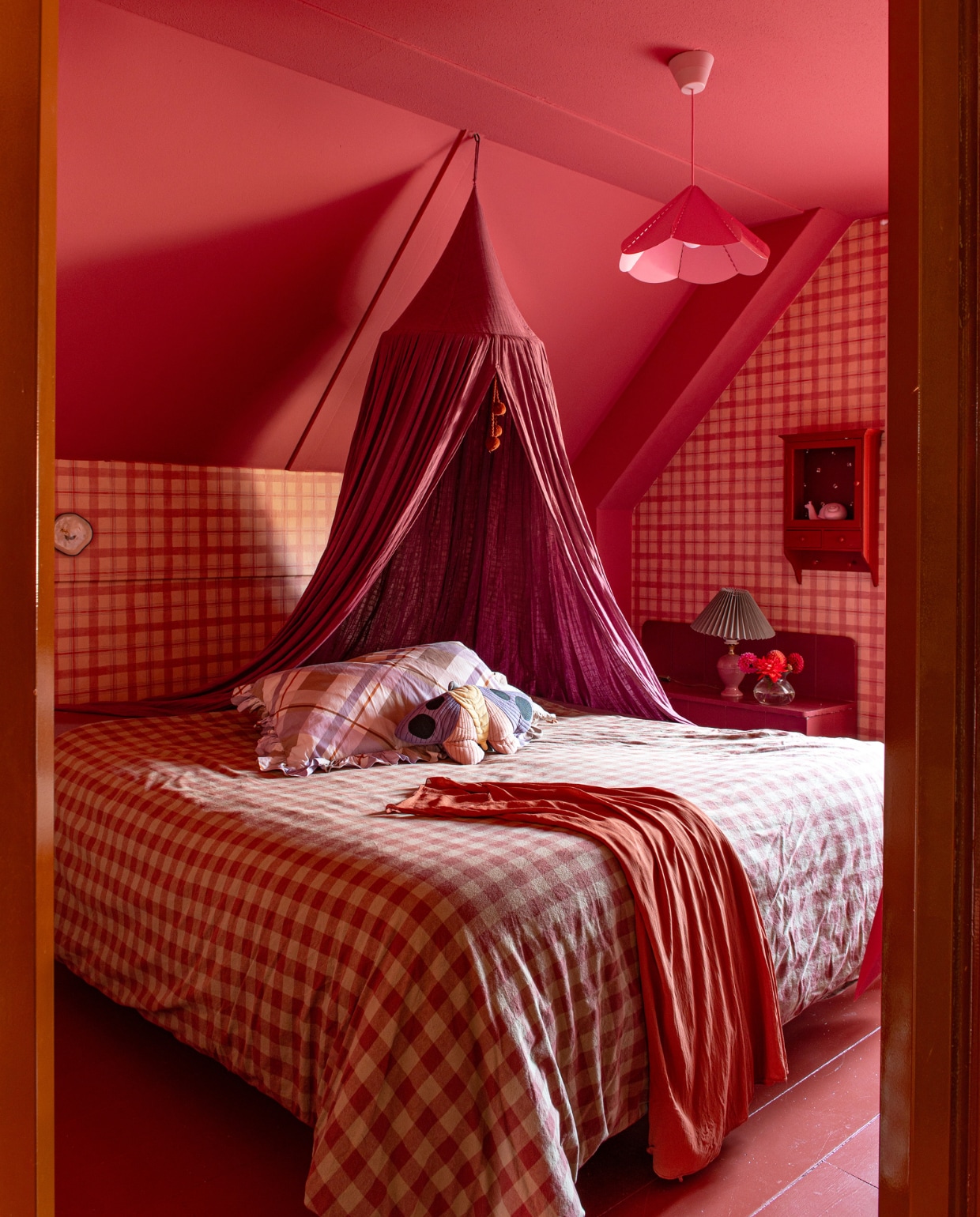 Muurverf Rhubarb en houtverf Very Well Red van Paint &amp; Paper Library. Behang Swiet, wandkast Sklum, kast Olli Ella. Tafellamp vintage met kap van H&amp;M. Hemel Play at Slaep, beddengoed Mango, kussens Moozle, hanglamp Ikea. Overig onbekend. vtwonen 01-2024 | styling Linda van der Ham | fotografie Caroline Coehorst