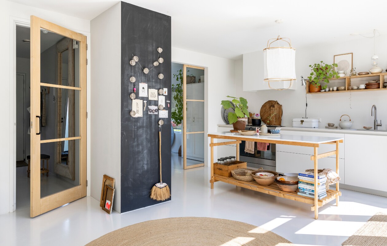 Keuken Mooiwerk Interieur. Schuifdeuren van essenhout laten maken door timmerman. Lamp Manggis Living. Keukeneiland zelf-gemaakt, schalen, kommen en kook-boeken BijDaan. Overig onbekend. vtwonen special binnenkijken 12-2023 | fotografie Margriet Hoekstra