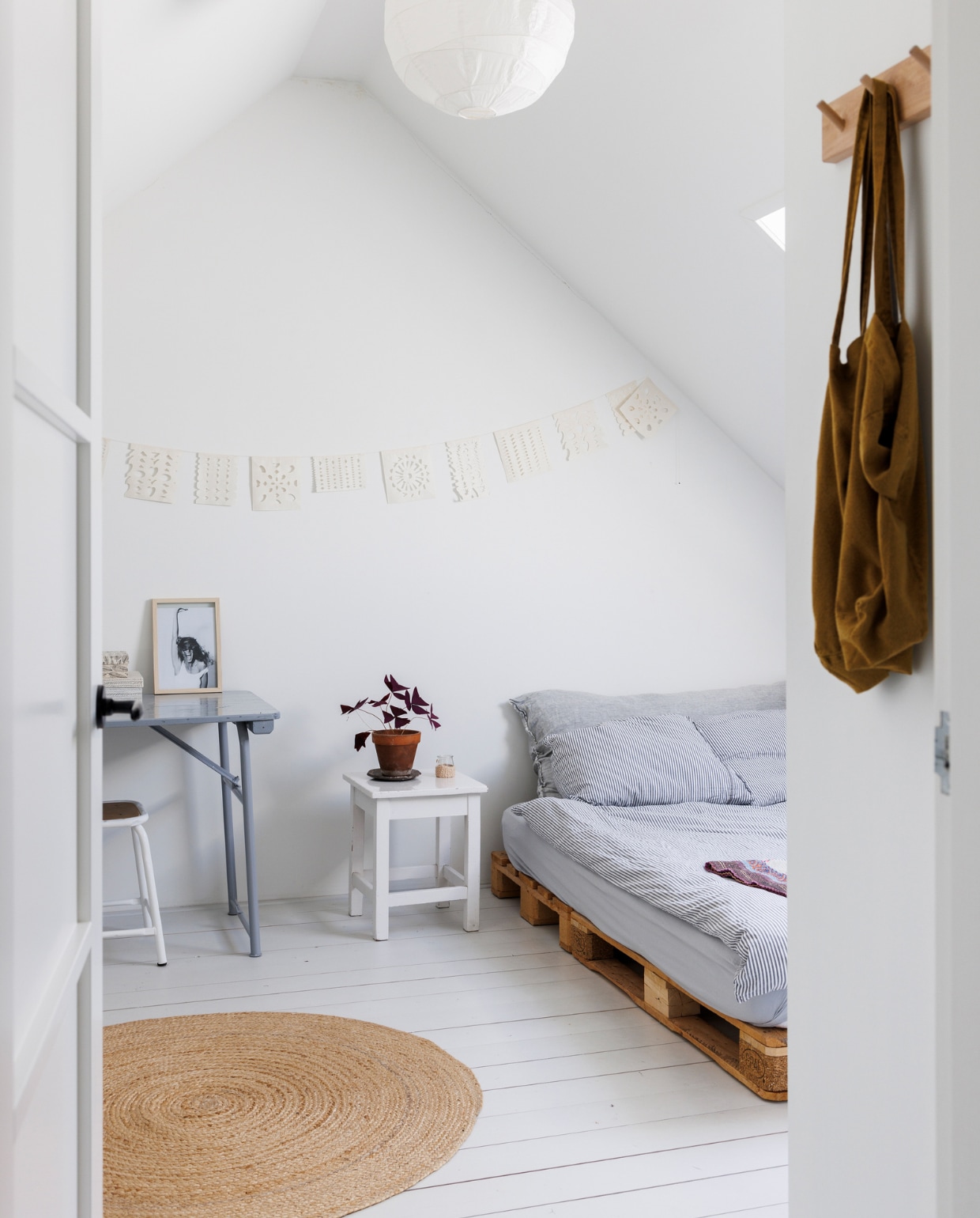 Bed zelfgemaakt van pallets. Slinger Atelier Sukha, bijzettafel Combitex, kleed BijDaan. Overig onbekend. vtwonen special binnenkijken 12-2023 | fotografie Margriet Hoekstra