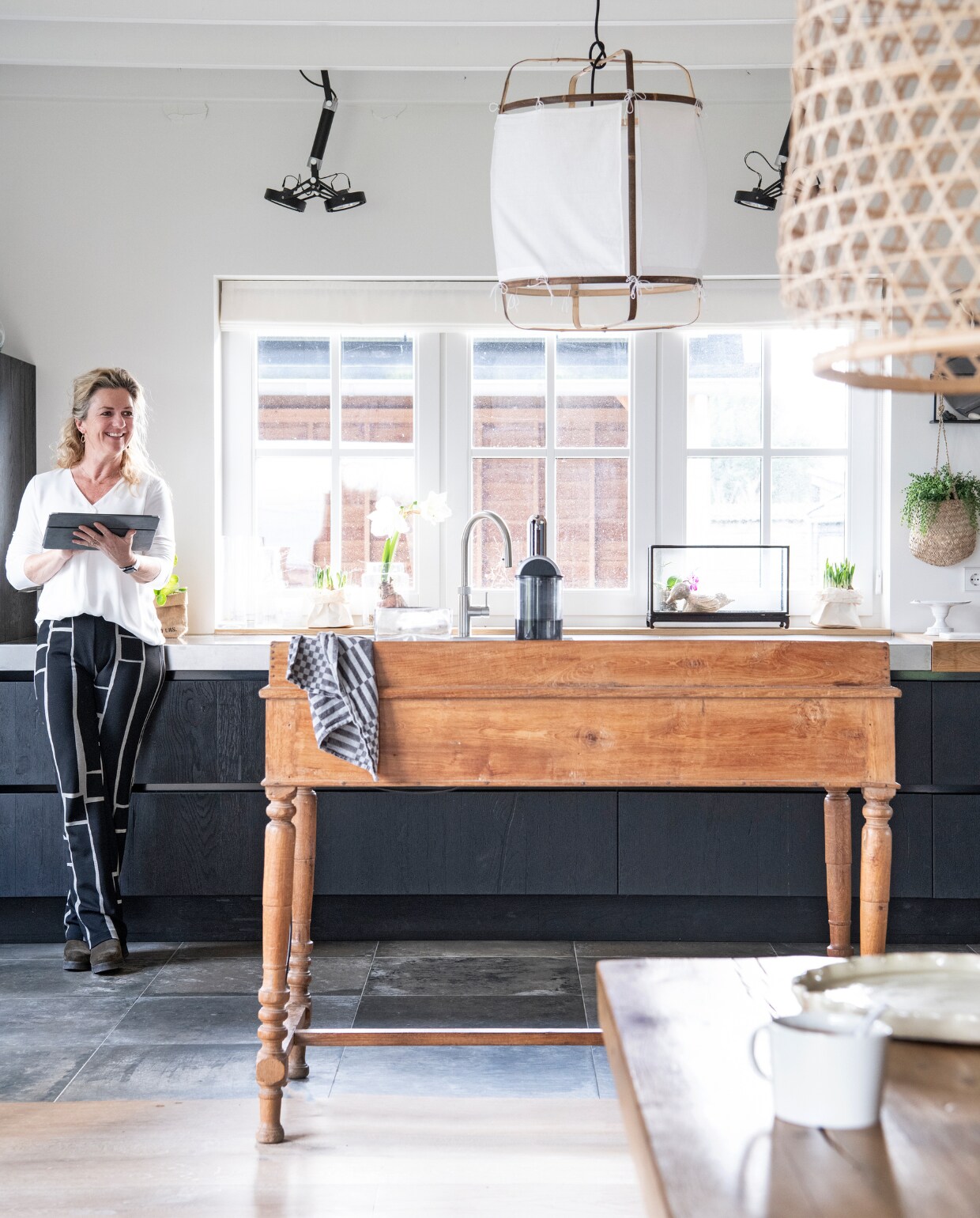 Keuken met rvs-werkblad Buro Logge, oude \ lessenaar rommelmarkt, witte hanglamp Wonen met Lef. Spots Modular Nomad, vloertegels Kroon Vloeren in Steen, glazen bak in vensterbank Tica, hangplant Loods 5. vtwonen 13-2020 | productie Insidehomepage | styling Marlies Does | fotografie Louis Lemaire