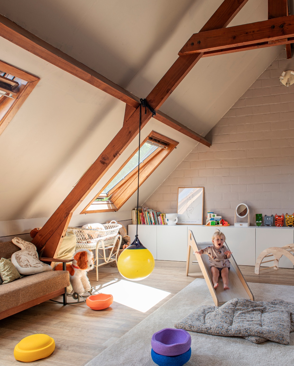 Vloer Van der Perre. Glijbaan Arthur &amp; Friends. Schommelbal Mamuli (bestaat niet meer). Kasten en tapijt Ikea. Bank vintage via Tims werk. Vloerkussens Sanne Boer. Speelgoed Stapelstein. Rotan wieg tweedehands. vtwonen 03-2023 | productie De Binnenkijkers | styling Jeske Weel | fotografie Caroline Coehorst