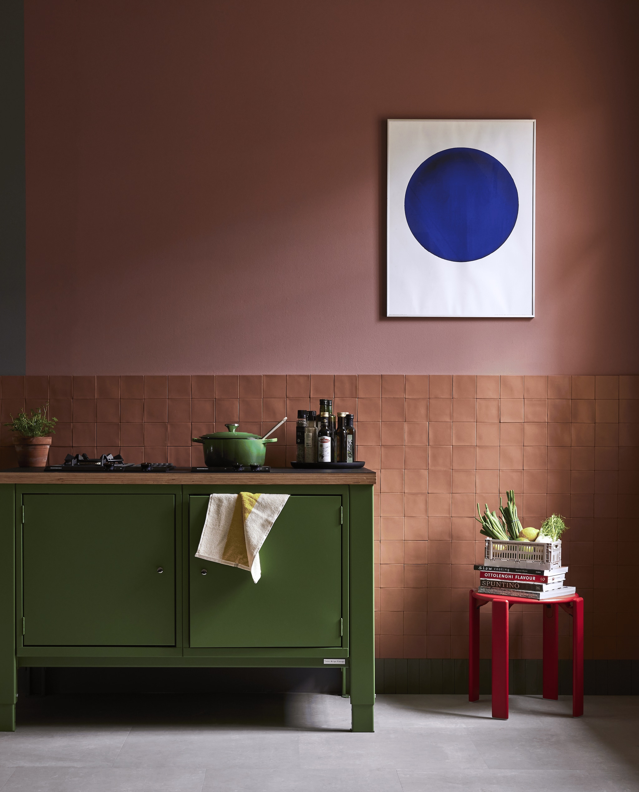 Muurverf Terra Pink van Lab Paint (vestingh.nl). Wandtegel Chop van vtwonen in Mattone, 10x10 cm, tegel als plint Chop van vtwonen in Kaki, 5x15 cm,(douglasjones.nl). Keukenblok geschilderd in kleur Ral 6011, resedagroen (thebigeasykitchen.nl). Pan van Le Creuset, zwart metalen dienblad van Zone Denmark (vtwonen.nl/shop). Rode kruk Rey, hout en gepoedercoat staal, polypropyleen krat (hay.nl). Affiche blauwe stip van Yves Klein (stedelijkmuseum.nl). Overig privbezit. vtwonen 04-2024 | styling Fietje Bruijn | fotografie Alexander van Berge