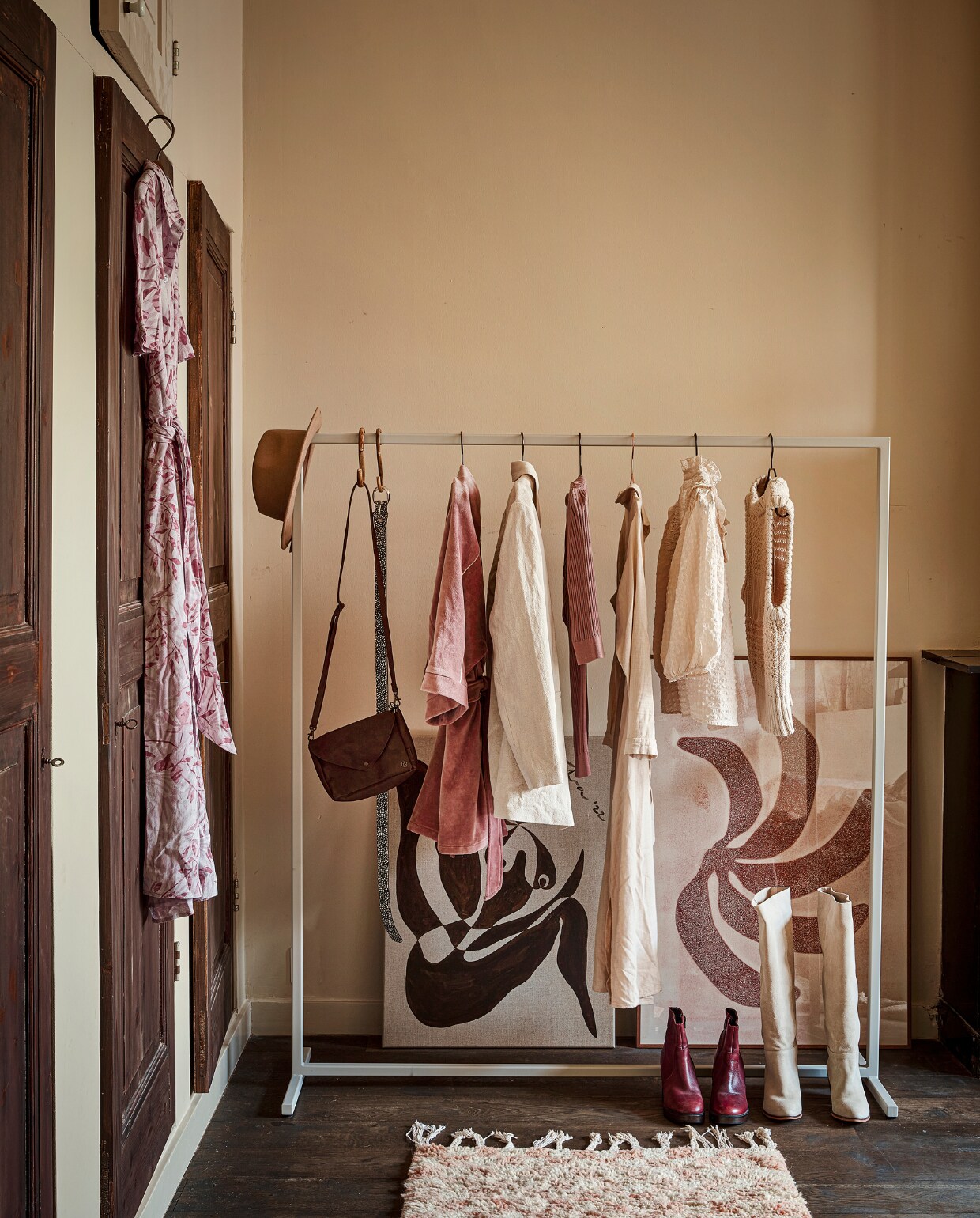 Gebloemde jurk aan deur € 99,99, leren tas € 34,99, riem € 32,50, gebroken wit colbert € 99,95, lange jurk € 89,95 (mensinkmode.nl). Wollen hoed € 34,95, bordeauxrode enkellaarzen € 69,- (@flowerchild.arnhem). Kledingrek Julie in RAL 7044, 140x157 cm € 299,18 (fashionracks.nl). Bamboe s-haken per stuk € 3,50, gebroken witte smock top € 69,99, gebreide waistcoat € 99,95 (loftloft.nl). Velours badjas € 150,- (@studio.cherrymoon). Oudroze shirt met streep € 39,95, hoge laarzen € 129,95 (@sparqelle). Kunstwerk No.22 Engelen, 60x80 cm € 485,- (sifravieten.com). Handgemaakte print Let’s Go Bananas, 70x100 cm € 249,- (enkelartstudio.com). Berber vloerkleed, 77x178 cm € 275,- (thesouks.nl). vtwonen 10-2022 | styling Demelza Krens | fotografie Peggy Janssen