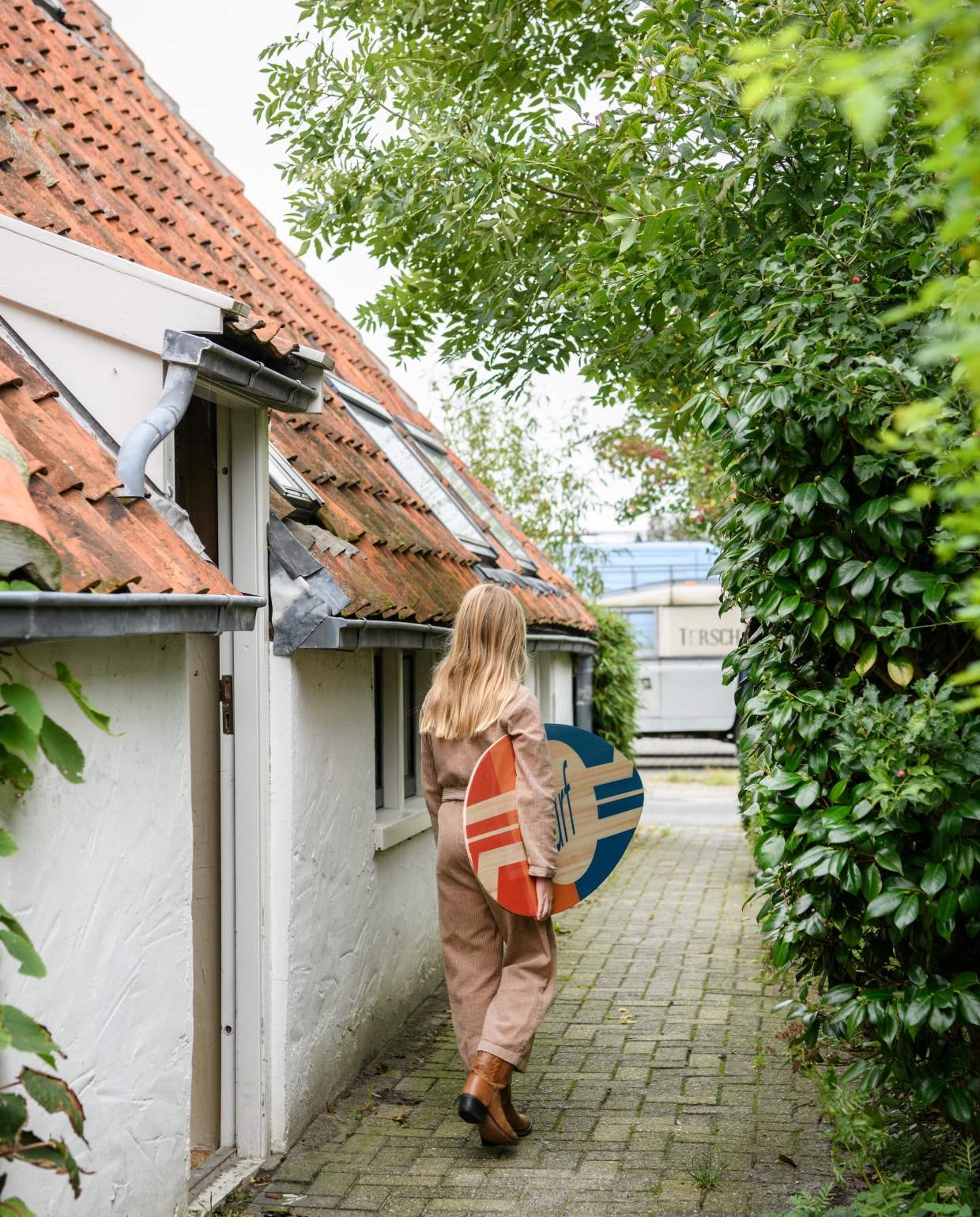 Neve loopt net de deur uit van haar achterhuis op een boerderij in Hoorn. Surfbord onbekend. vtwonen 02-2024 | productie Inside Homepage | styling Esther Loonstijn | fotografie Louis Lemaire
