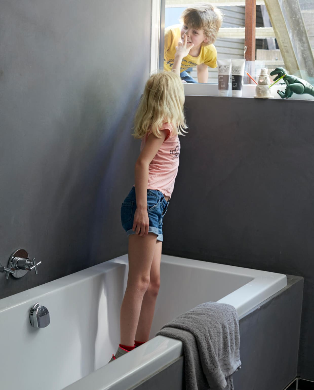 Kiki in de badkamer waar – in het droge gedeelte – de muur is gestuukt met antraciet tadelakt voor een mooie betonlook. De tubes douchegel en bodylotion zijn van Leeff. vtwonen 07-2014 | Fotografie Tjitske van Leeuwen | Styling Marianne Luning
