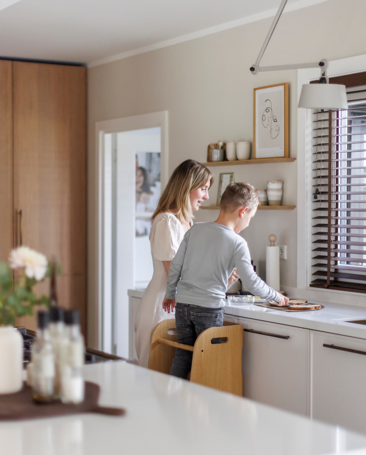 Muurverf Sandy Beach van Flexa. Op maat gemaakte keuken en hoge kast Keukenstudio Stormink. Bamboe jaloezieën Topjaloezieën, wandplanken Studio Harm en Elke, hanglamp Tonone, opstapkruk Curve Lab, poster Desenio, servies Mento. Overig onbekend. vtwonen 03-2024 | Fotografie Margriet Hoekstra