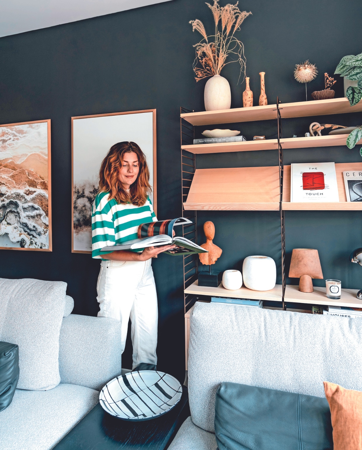 Myrthe in haar nieuwbouwhuis in Berkel en Rodenrijs. Muurkleur Night Sky van Lab Paint, wandkast String Furniture. In de kast: twee kleine vazen en schaal uit keramiekshop in Zuid-Frankrijk, platte vaas Bolia. Boeken: Tales from the Roads Less Travel, Vincent van Duysen Works 2009-2018, The Touch: Spaces designed for the Senses, Think New Modern. Alabaster theelichten Enter the Loft, bruine vaas 101 Copenhagen, geurkaars Parks London, modulaire bank Rolf Benz, baklijsten Goedman Lijstenmakerij met eigen fotografie. Overig onbekend. vtwonen 02-2024 | fotografie Myrthe Slootjes