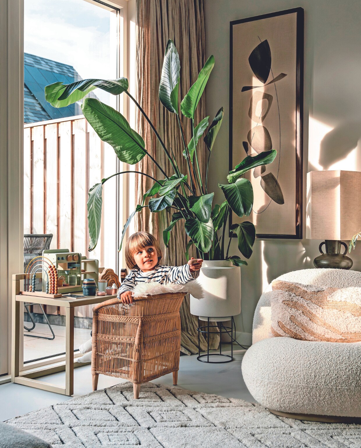 Muurkleur Ammonite van Lab Paint, vloer beton ciré van Boncreations, linnen gordijnen Flax van By Mölle, kunst Symbiose van Atelier De Rijk, pot met standaard Bolia, plant Strelitzia, kinderbureau Little Architect van Ferm Living, kinderstoel Malawi van People of the Sun, speelgoedkeuken Ikea. Telraam en koffiezetapparaat Little Dutch. Fauteuil Pacha van Gubi, kussen HKliving, vloerkleed Armadillo, stoel buiten Grace van Exotan. vtwonen 02-2024 | fotografie Myrthe Slootjes