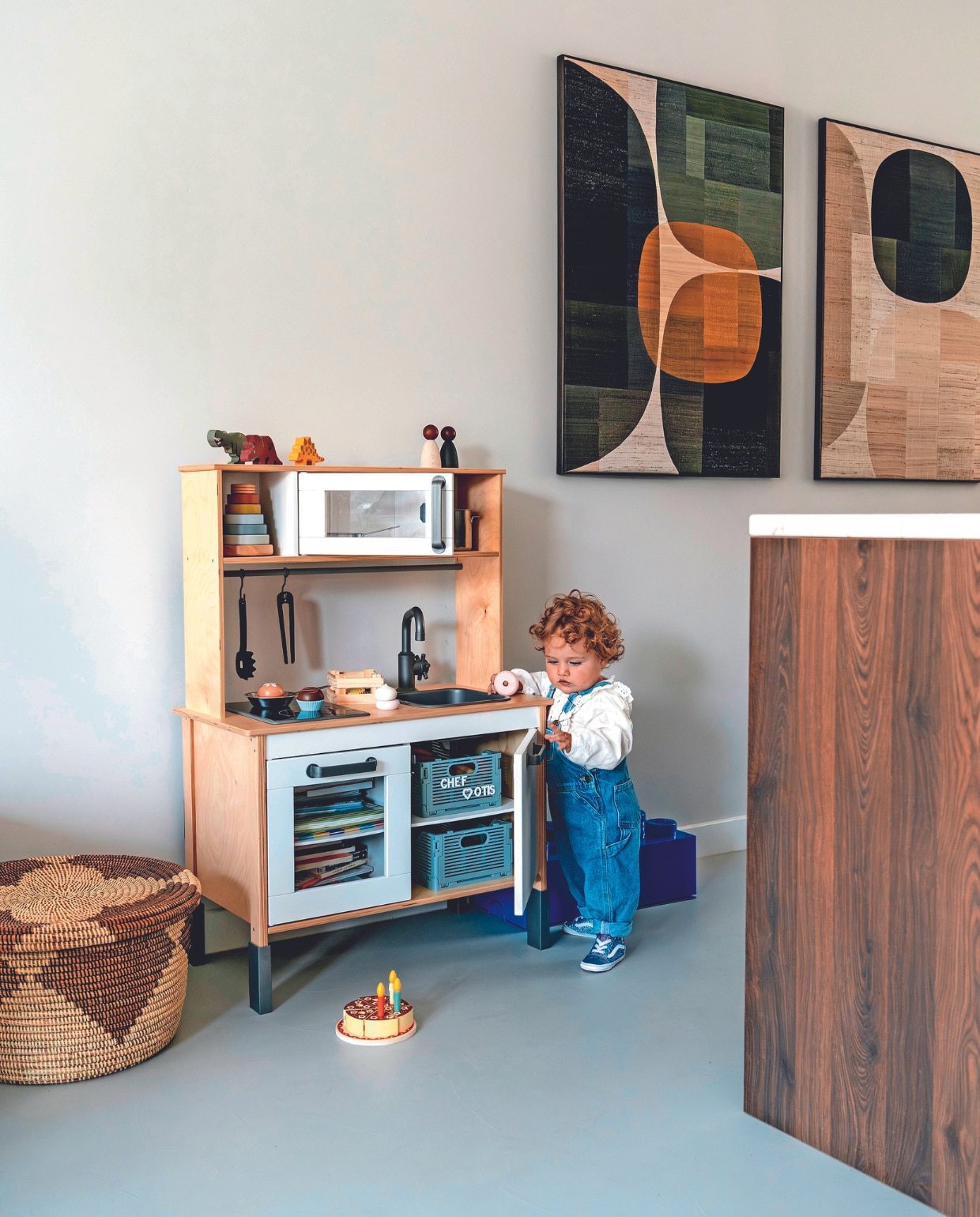 Muurkleur Ammonite van Lab Paint, vloer Beton ciré van Boncreations, kunstwerken van X+L, mand uit Zuid-Frankrijk, op maat gemaakte keuken KeukenVision. Speelgoedkeuken en gerei Ikea. Houten dino’s Tender leaf Toys, poppen Grapat, toren Little Dutch. Kratten en taart Hema. Legoblok-opberger Bol. vtwonen 02-2024 | fotografie Myrthe Slootjes | tekst Mirjam Rosema-Verhulst