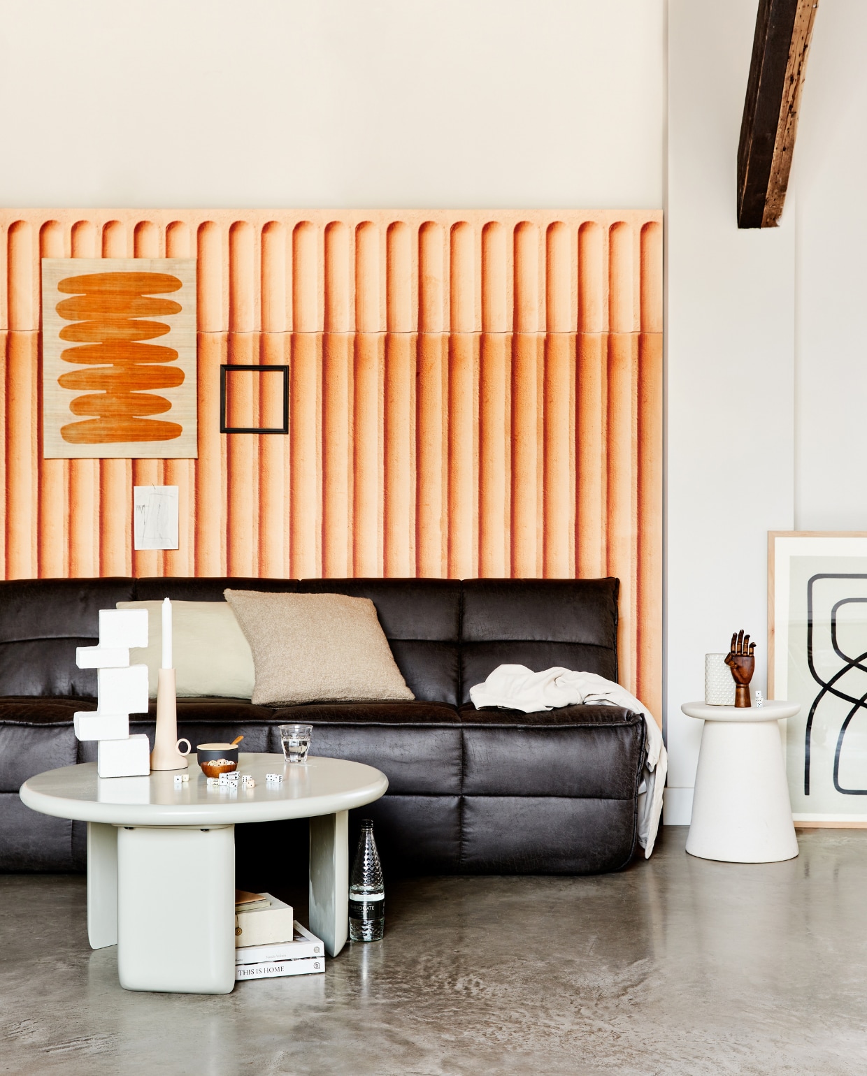 Antracietkleurige 3-zitsbank Cluster, vegan leer, 210x90x80 cm (bxdxh), ook verkrijgbaar in andere stoffen, vanaf € 999,-. Witte keramieken bijzettafel/kruk Button, ook verkrijgbaar in warm groen en taupe, 35x45 cm (Øxh) € 129,-. Bijzettafel Beach, medium 80x41 cm (Øxh) € 399,-, ook verkrijgbaar in small, 64x51x53 cm (lxbxh) € 319,-.m.m.v. vtwonen.nl (wandkleed Minimalism van Urban Nature Culture, wit object op tafel en kussens van vtwonen, suikerpot van Stelton, artwork rechts van HKliving, kandelaar van Pols Potten), sukha.nl (kaart aan de wand, papieren doosje onder tafel), behangfabriek.com (behang met bogen in terra), sostrenegrene.com (object hand). Overig privébezit. vtwonen 2-2022 | productie Tanja Saarberg | styling Marlies Does | fotografie Bart Brussee | assistentie Neda Farzanyar, Judie Jonker